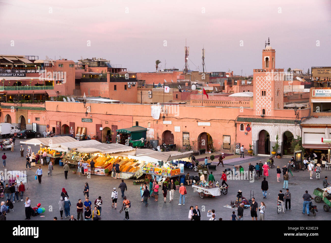 MARRAKESH, MOROCCO - APR 29, 2016: Mosque and restaurants with tourists near the souks on the Djemaa-el-Fna square in Marrakesh. Stock Photo