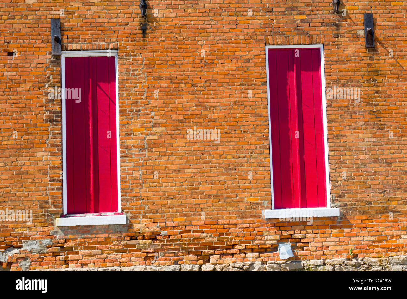 colorful pattern of a red door against a orange brick background Stock Photo