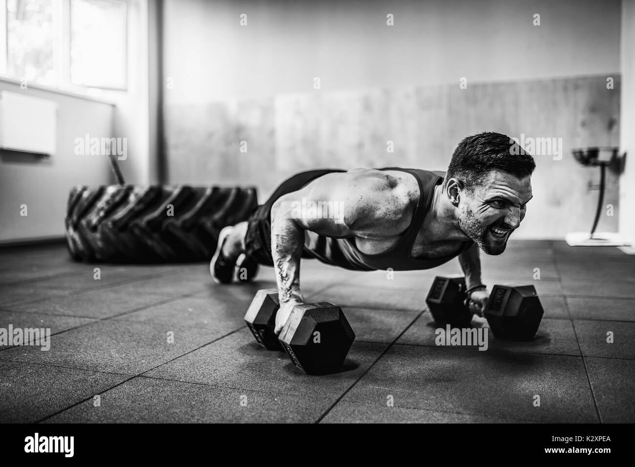 Muscular man doing pushup exercise with dumbbell Stock Photo