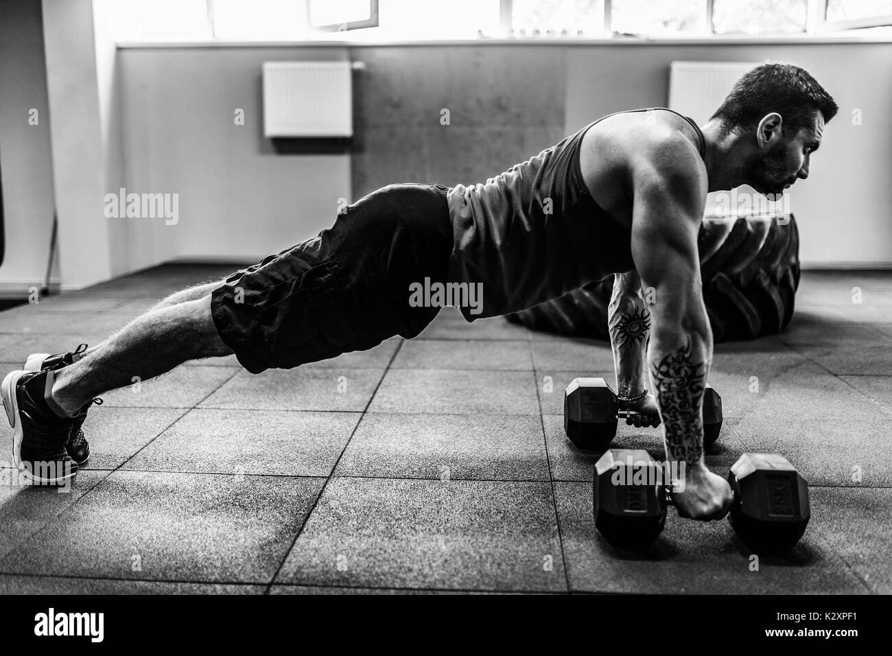 Muscular man doing pushup exercise with dumbbell Stock Photo
