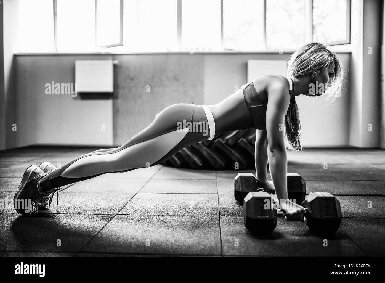 Attractive young woman is doing plank exercise while working out in gym Stock Photo