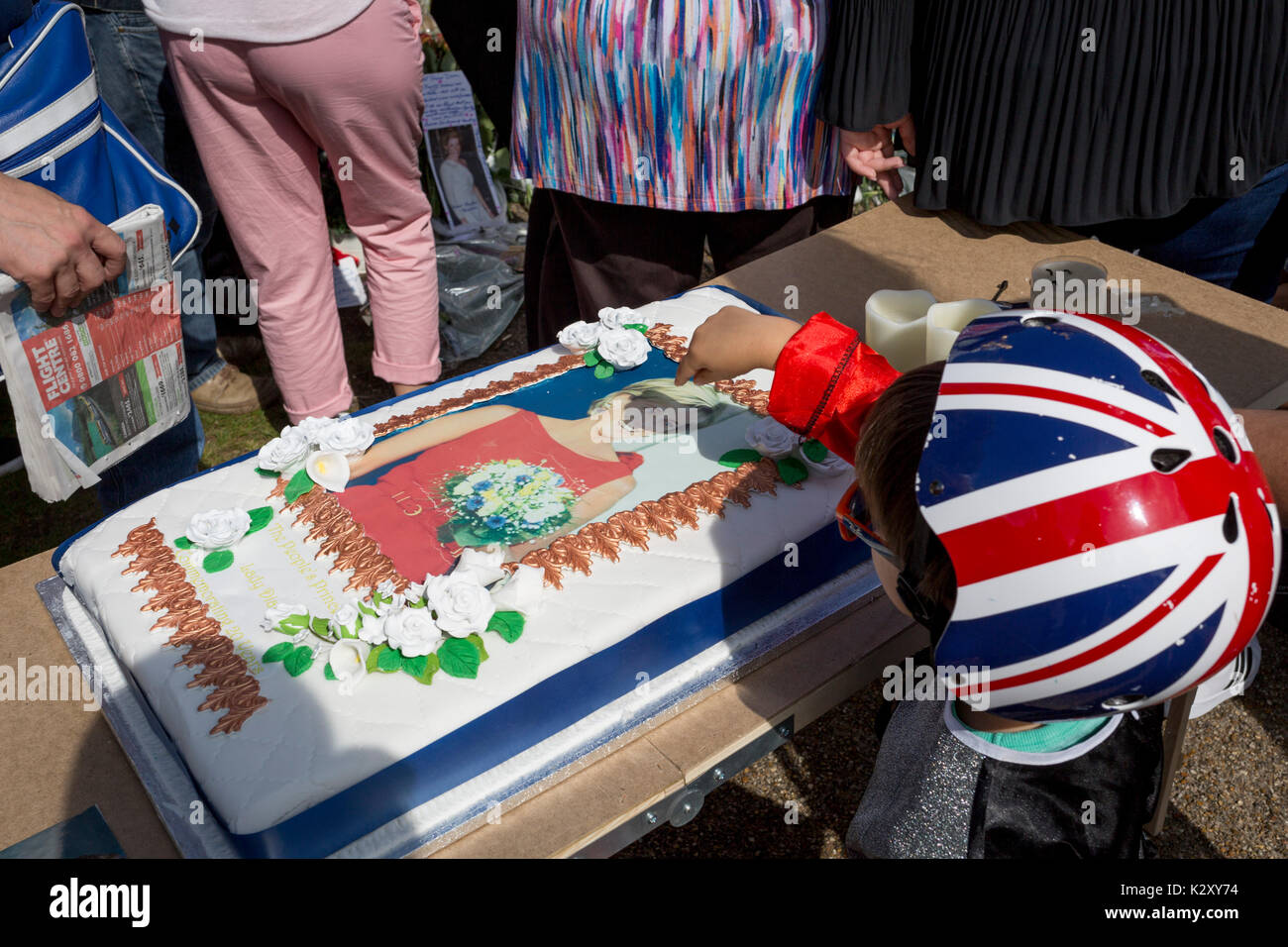 As crowds of royalist well-wishers gather, a spontaneous memorial of flowers, photos and memorabilia grows outside Kensington Palace, the royal residence of Princess Diana who died in a car crash in Paris exactly 20 years ago, on 31st August 2017, in London, England. In 1997 a sea of floral tributes also filled this area of the royal park as well as in the Mall where her funeral passed. Then, as now - a royalists mourned the People's Princess, a titled coined by the then Prime Minister Tony Blair. Stock Photo