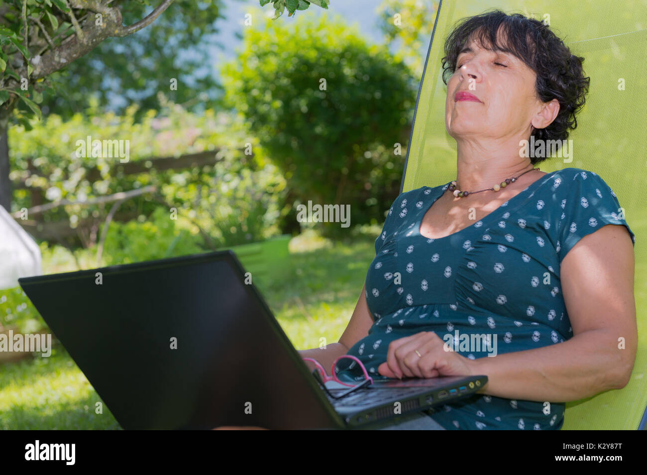 a mature woman relaxing resting on the deck chair in garden Stock Photo ...