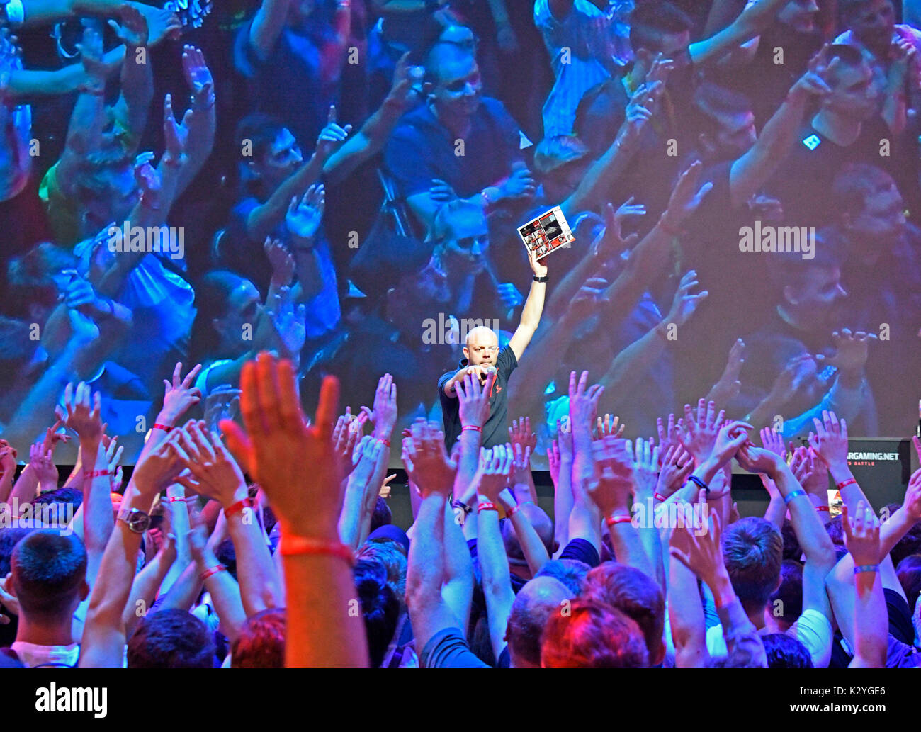 Presenter distributes free computer games to cheering crowd of young people in front of the presentation stage of Wargaming.net at Gamescom 2017, Europe's largest exhibition for video and computer games from 22nd to 26th August. 2017 in Cologne, NRW, Germany Stock Photo