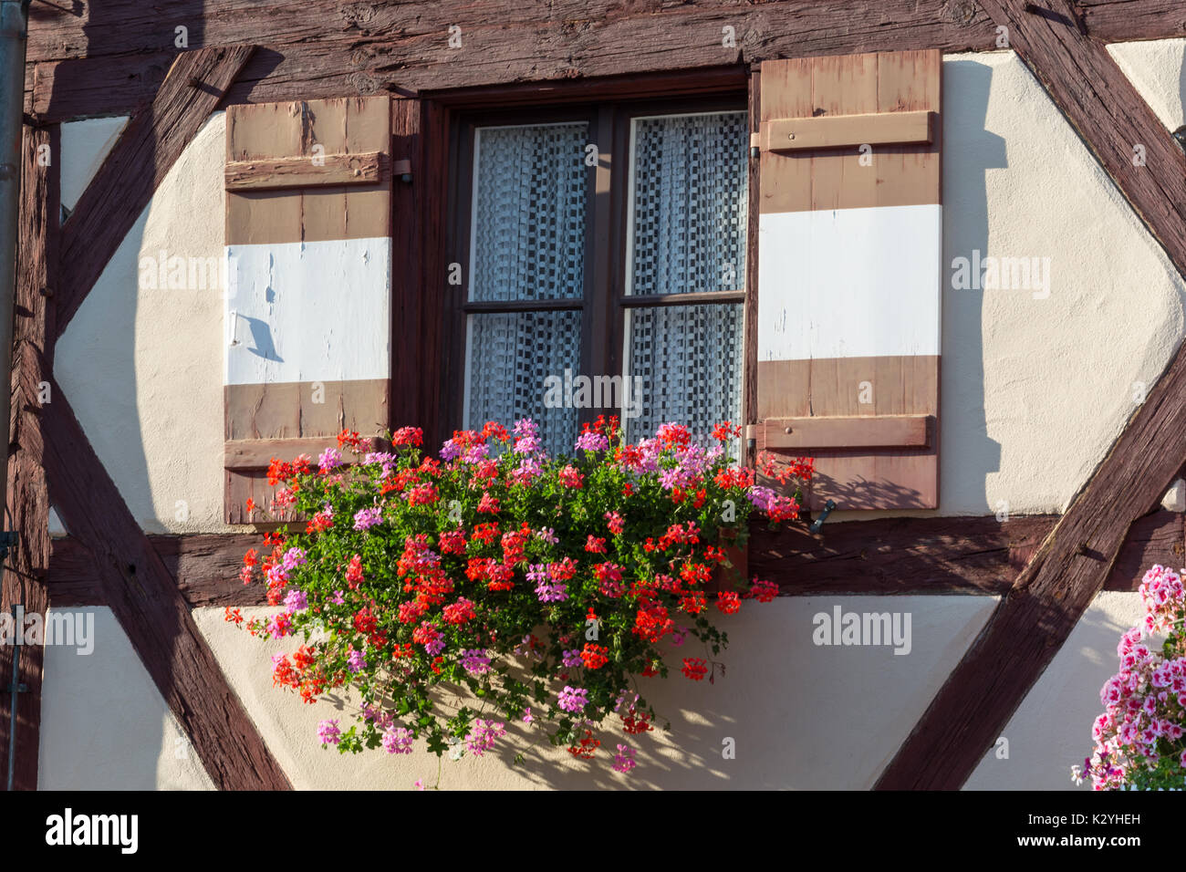 Half-timbered house with window shutters and colorful flowers Stock Photo