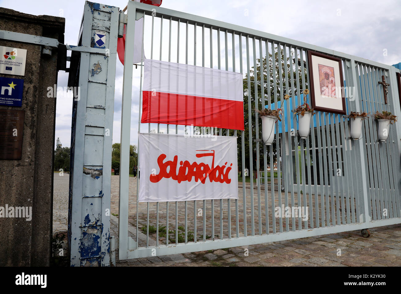 The entrance to the Gdańsk Shipyards, with a Polish flag and a flag bearing the logo of the Solidarity (Solidarność) union, in Gdańsk, Poland on 20 Au Stock Photo