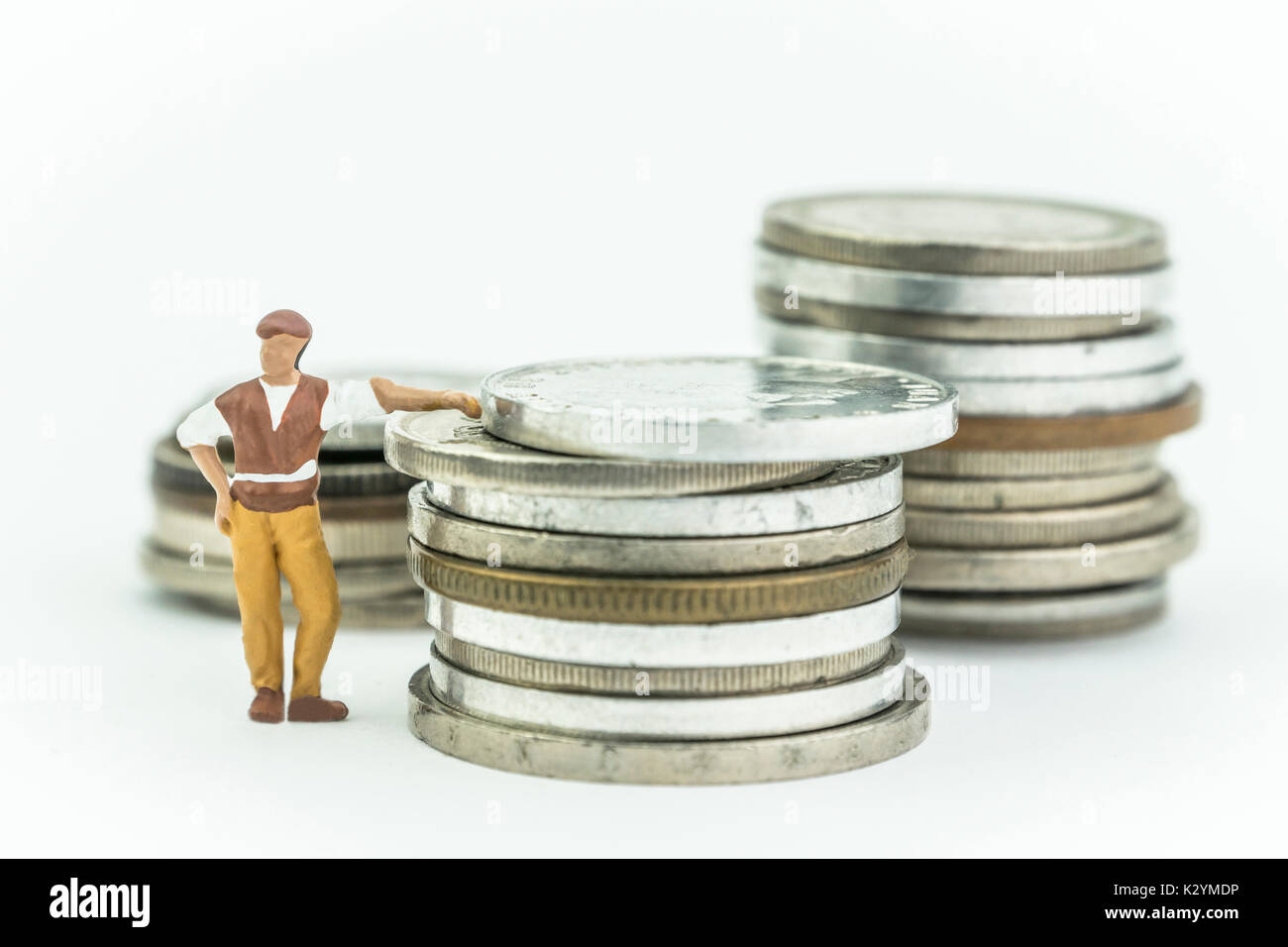 Miniature man next to a few coins, concept economy Stock Photo