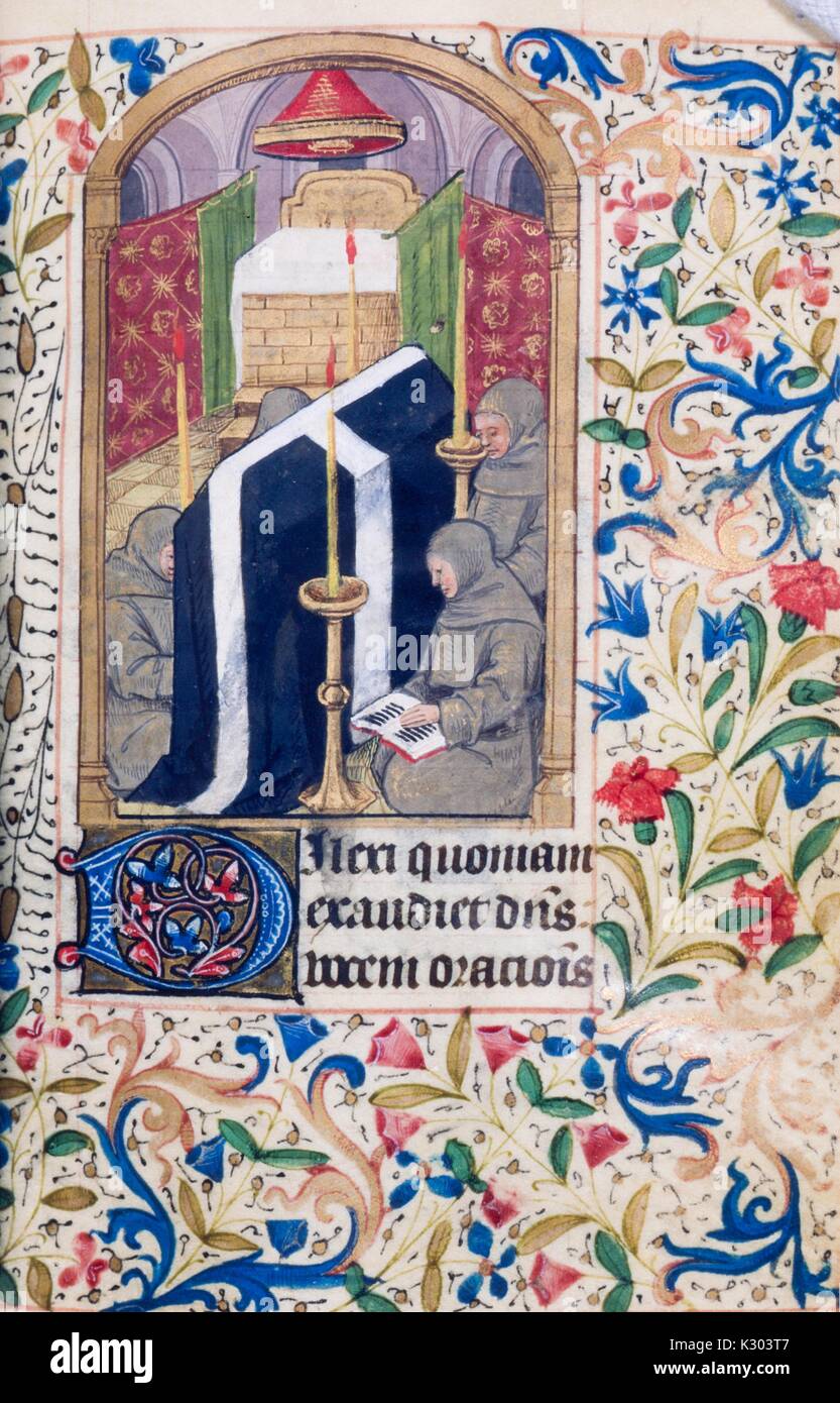 Illuminated manuscript page containing text, an ornate abstract floral border, and an illustration of kneeling praying figures from a 15th century Latin book of hours, 1450. Stock Photo