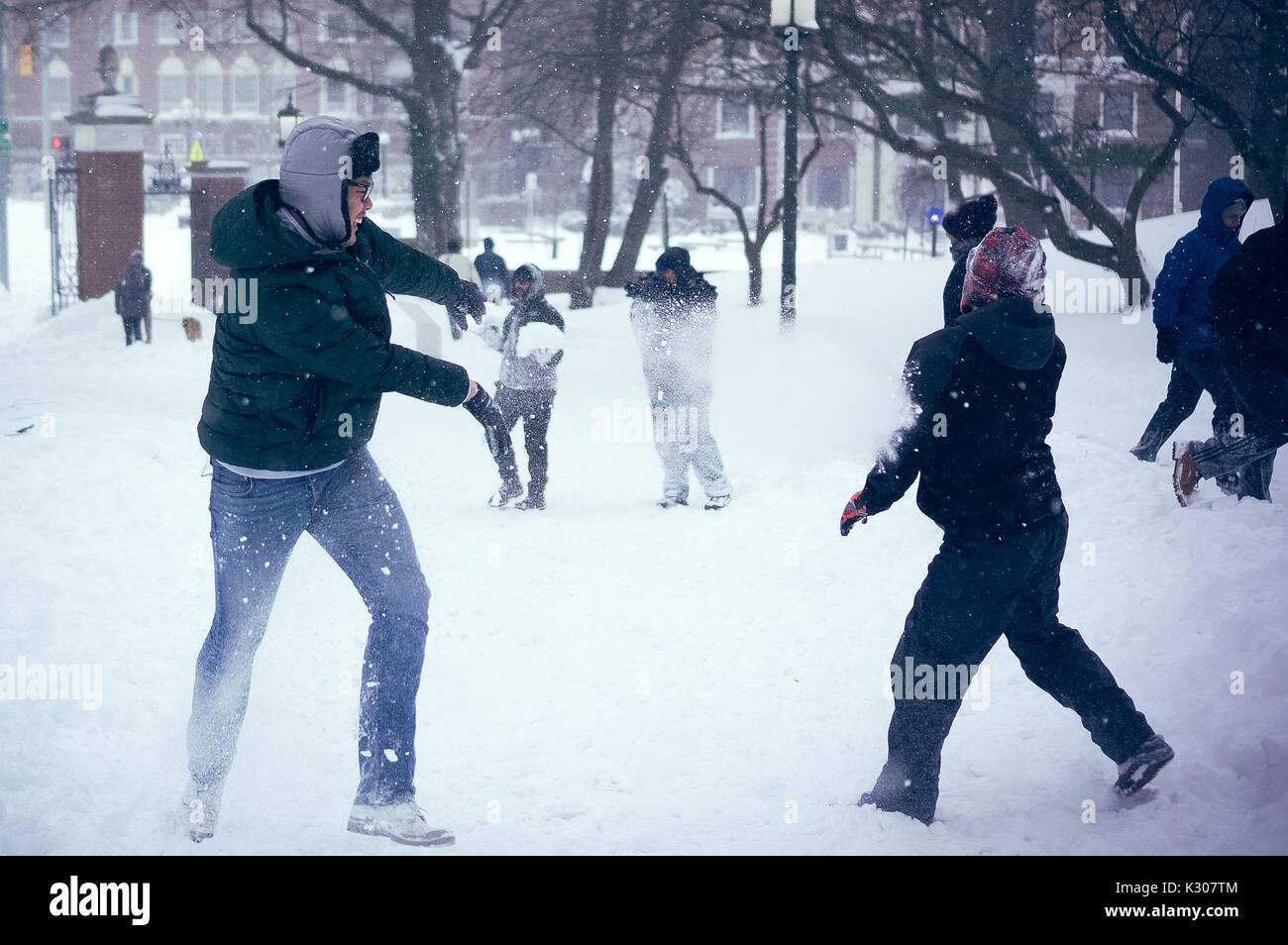 Students get hit by snowballs as others run and play during a massive snowball fight on a snow day at Johns Hopkins University, Baltimore, Maryland, 2016. Stock Photo