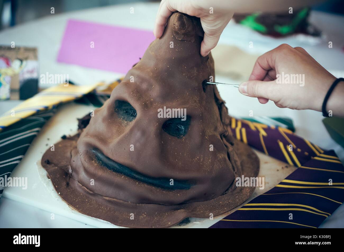 An undergraduate college student cuts her Harry Potter cake during Johns Hopkins University's annual 'Read It And Eat It' Edible Book Festival on the Homewood campus in Baltimore, Maryland, 2016. Courtesy Eric Chen. Stock Photo