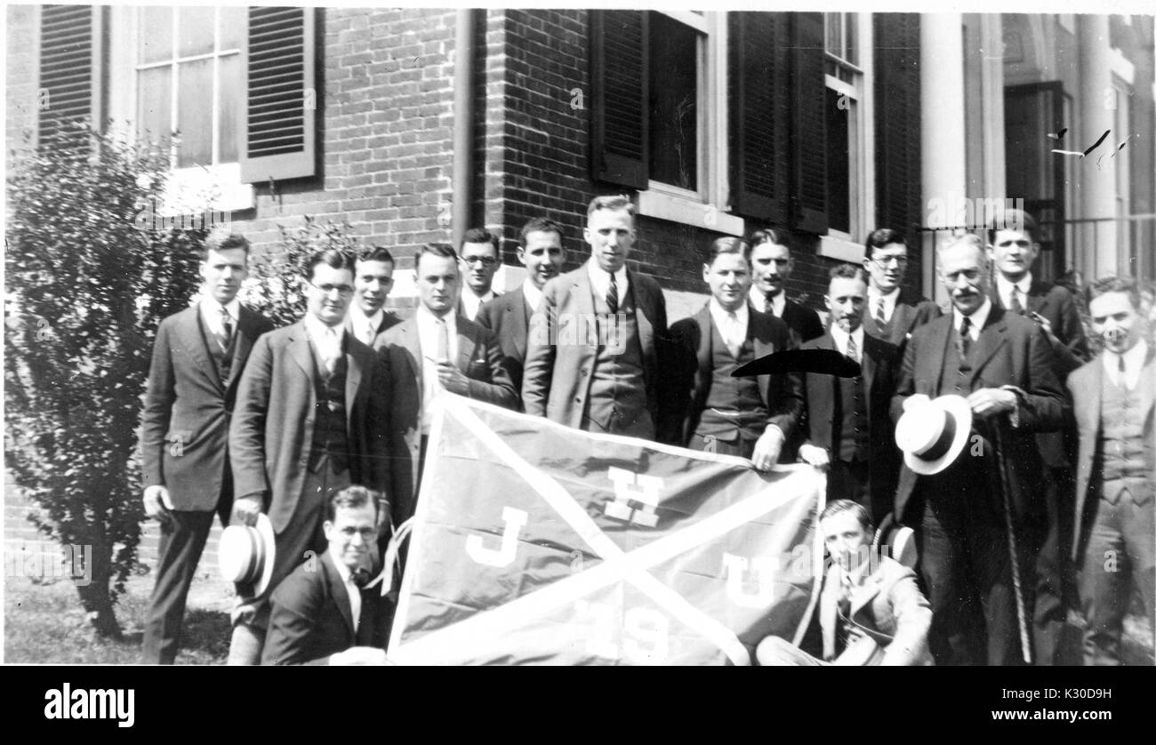 Men dressed in suits holding a flag at the fifth reunion at Class of 1919 outside of Homewood House at Johns Hopkins University, Baltimore, Maryland, June 7, 1924. Stock Photo