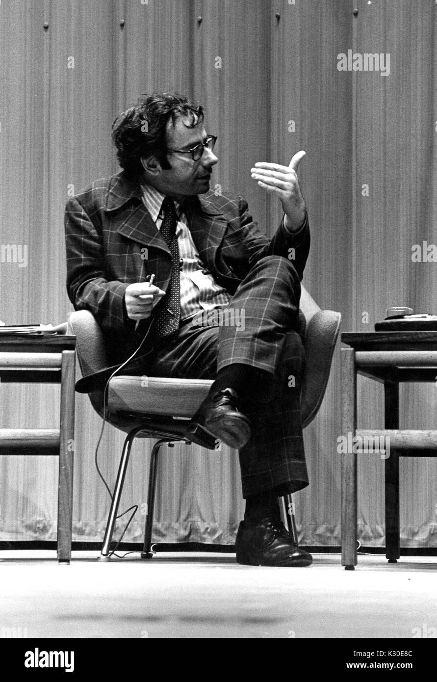 Prominent American social critic and author Marcus Raskin on stage at American University Symposium sitting on a chair wearing a suit, February 21, 1976. Stock Photo