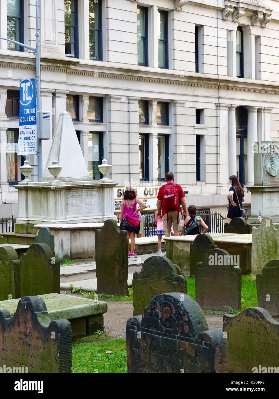 Trinity Church, Wall Street and Broadway, New  York, USA. Family looking at grave markers, including Alexander Hamilton's, in Trinity Churchyard. Stock Photo