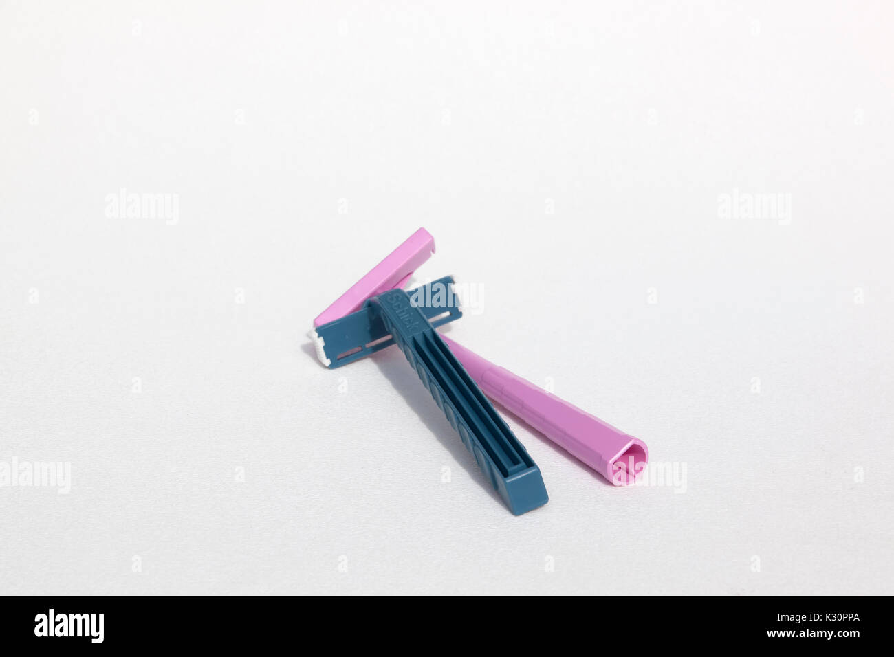 A blue Schick disposable & pink Bic disposable razor both made from the plastic, polypropylene. Stock Photo