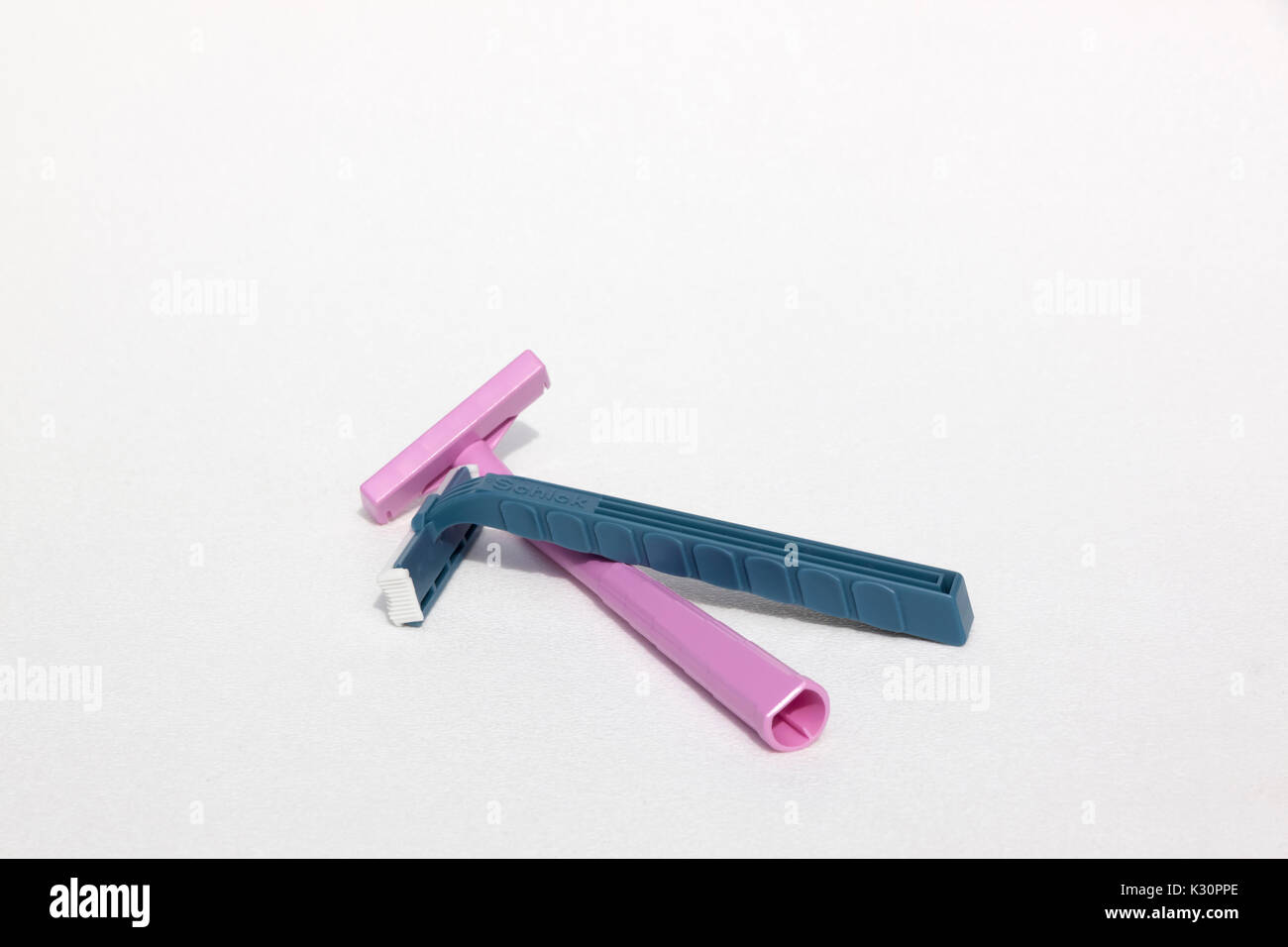 A blue Schick disposable & pink Bic disposable razor both made from the plastic, polypropylene. Stock Photo