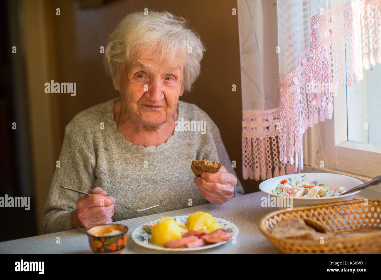 An elderly woman eat sitting at dinner table at home Stock Photo Alamy