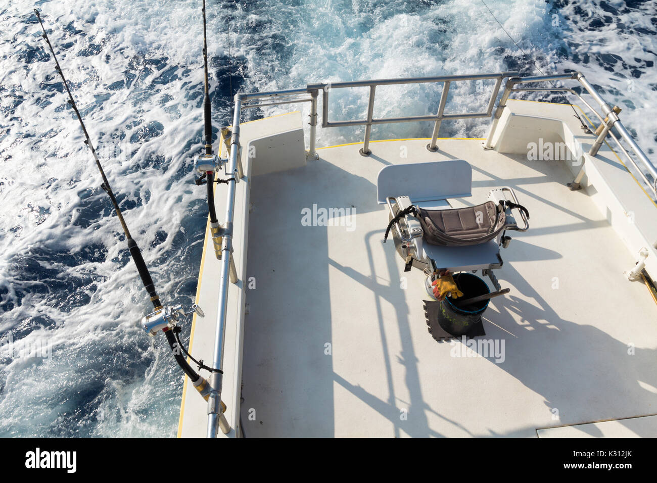 View from upper bridge of deep sea sport fishing boat with 2 lines set up and empty fish fighting chair. Offshore fishing in Hawaii. Stock Photo