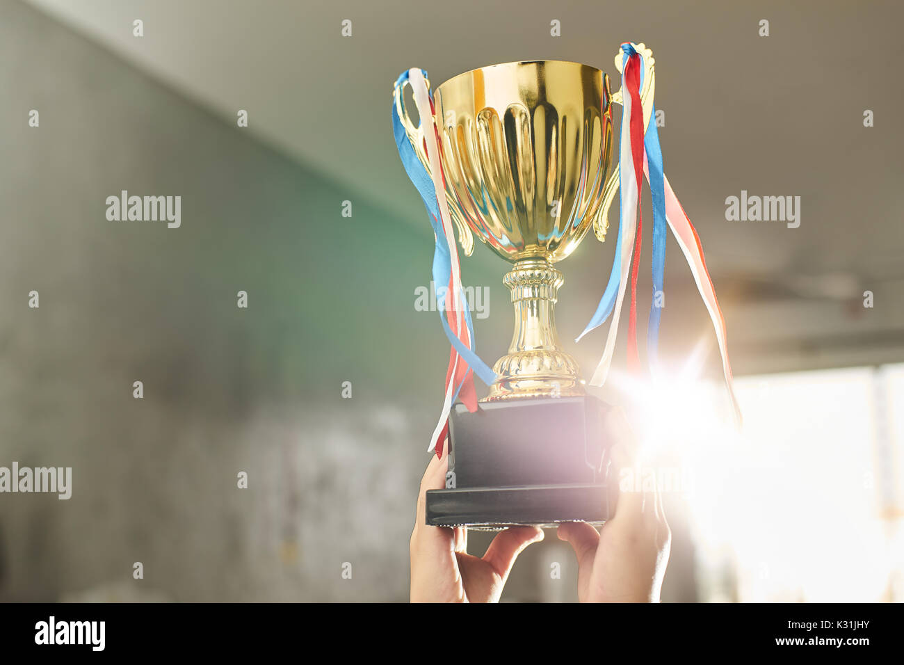 Young athlete holding up a gold trophy cup with space ready for your