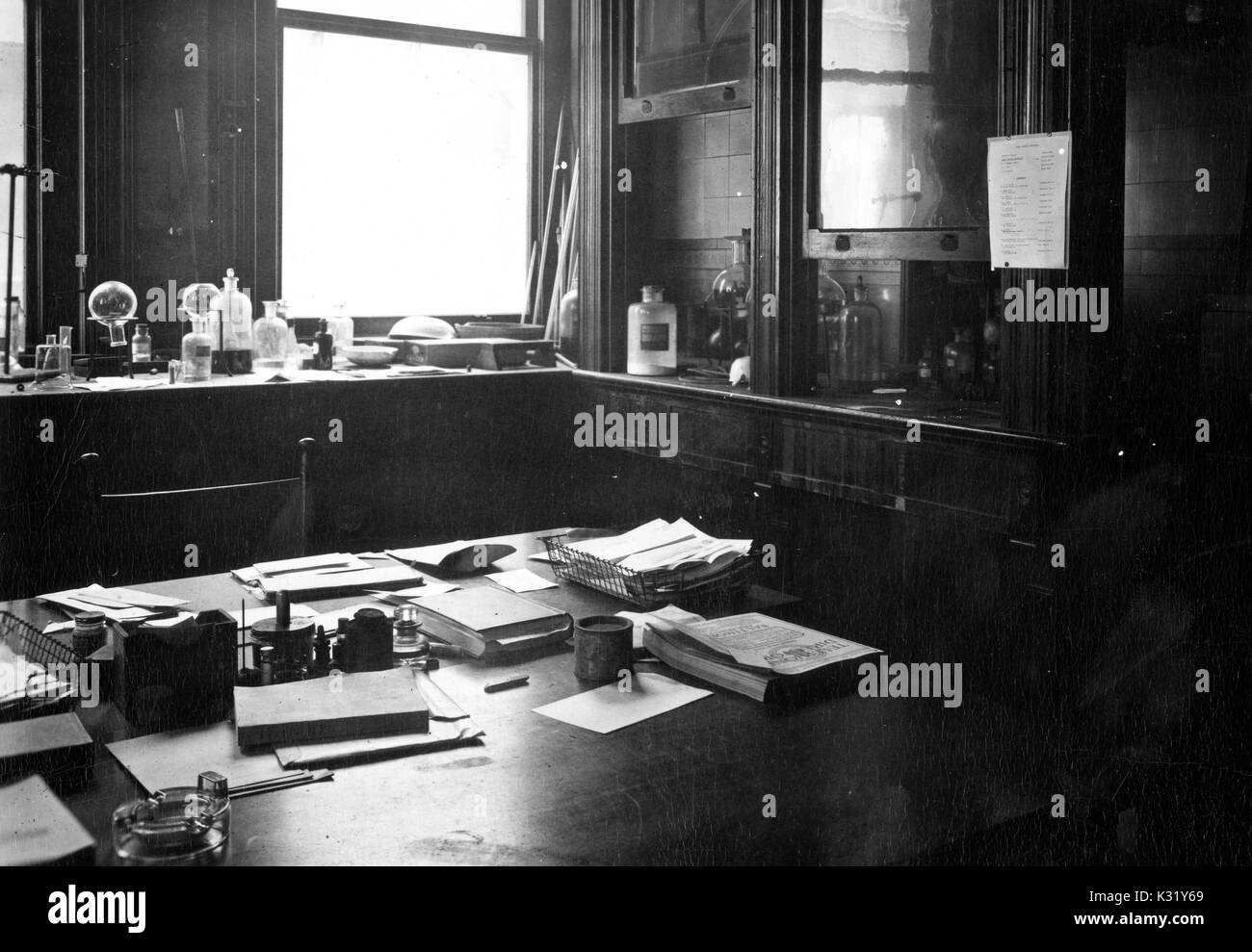 Grayscale photograph of interior of the office of Ebenezer Emmett Reid, chemist and physicist at Johns Hopkins University, with papers scattered at a desk and chemical glassware and equipment at a bench behind, inside the Chemistry Building at Old Campus, Baltimore, Maryland, 1924. Stock Photo
