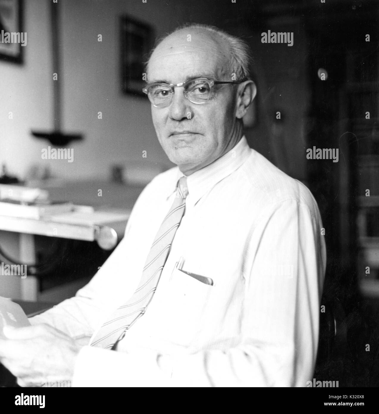 A seated portrait of prominent geologist Ernst Cloos wearing a suit and tie at 60 years of age in his office, 1959. Stock Photo