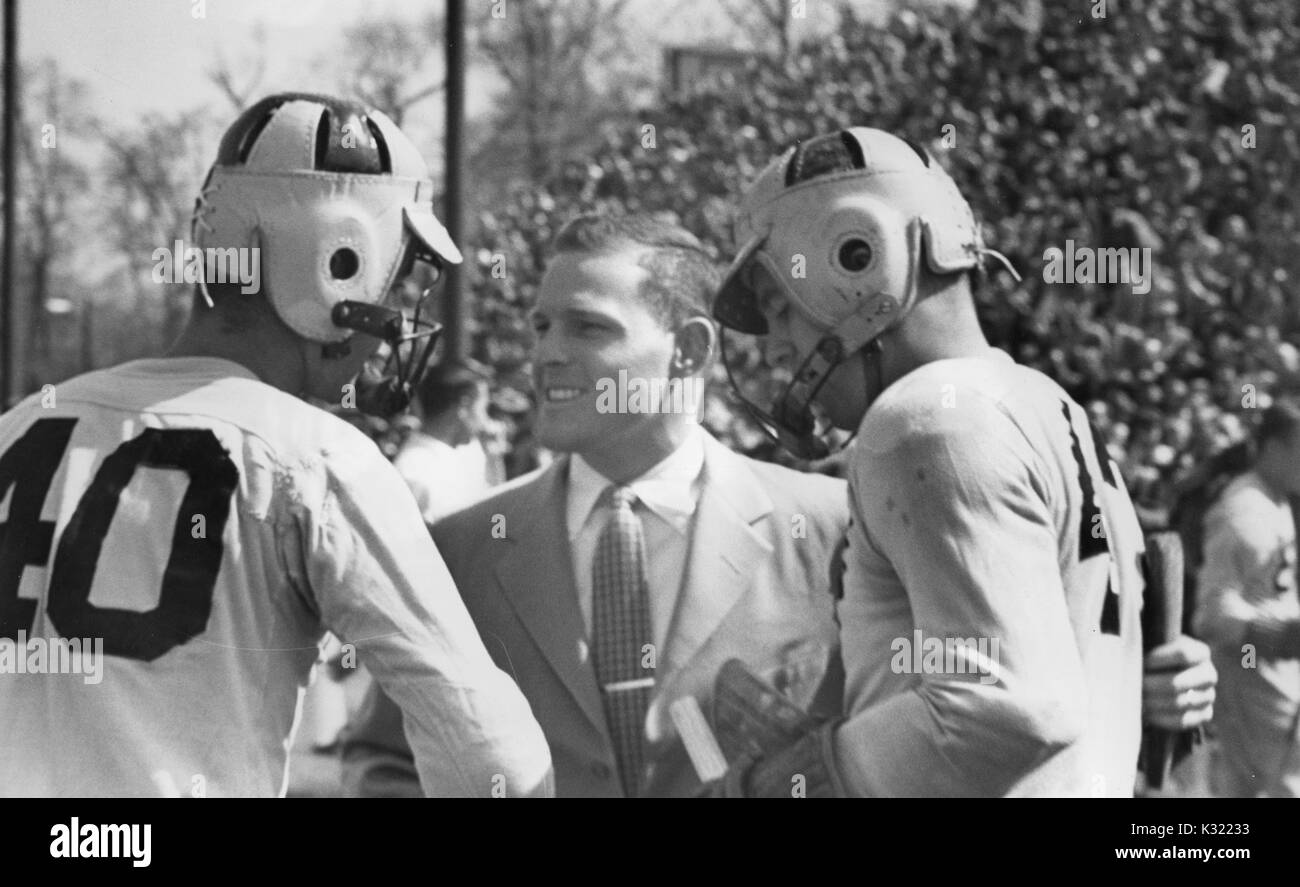 Sepia tone candid photograph of two co-captains of the men's lacrosse team at Johns Hopkins University, Joe Sollers and Byron Forbush, wearing uniform and headgear, shaking the hand of coach Smith at the end of the match, Baltimore, Maryland, June, 1951. Stock Photo