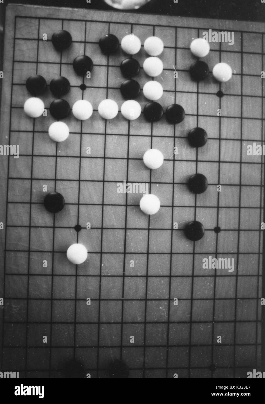 The board during a game of Go, an old Asian strategy game, with white and black stones arranged on the grid, 1950. Stock Photo