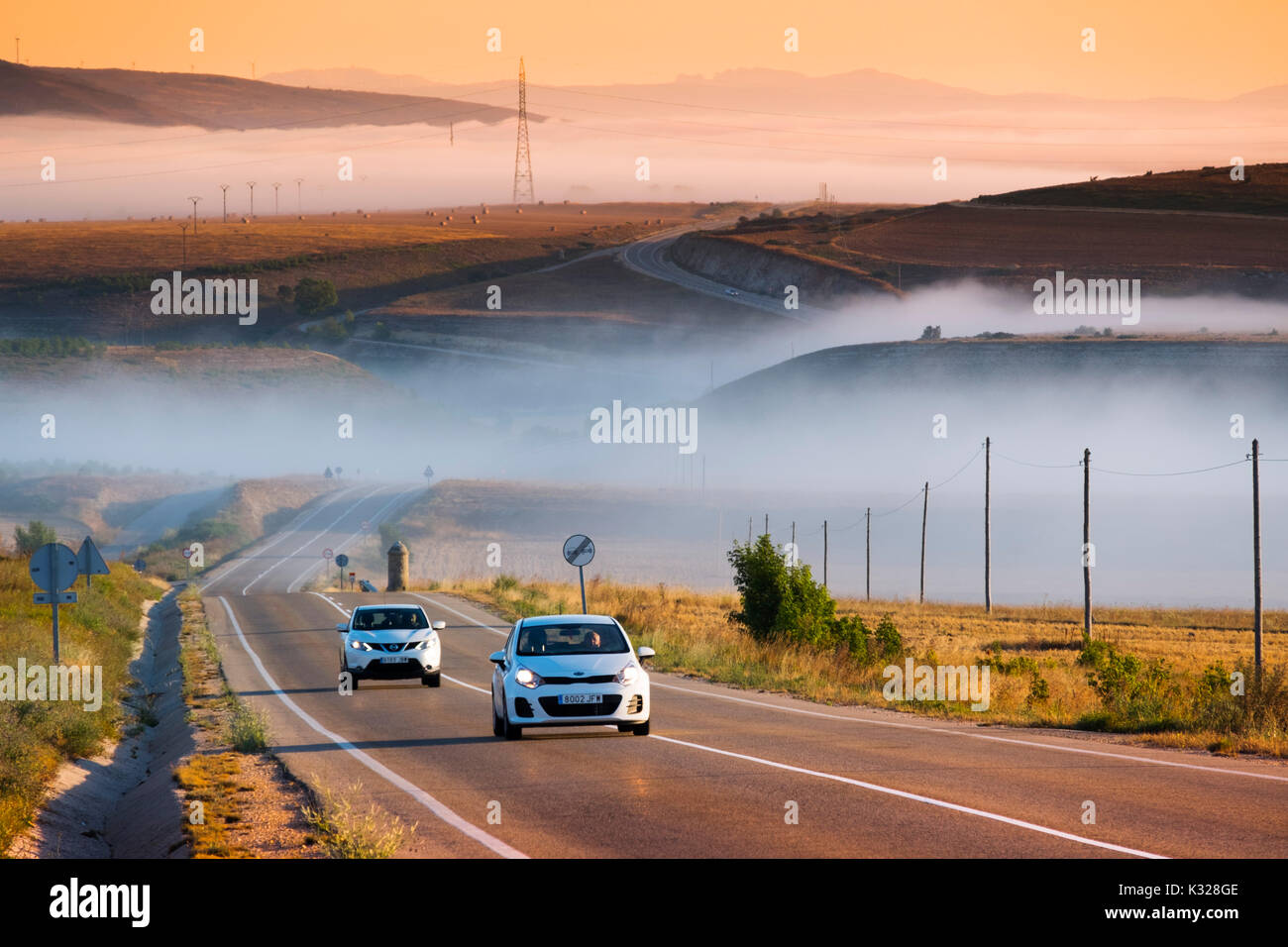 Road with cars at sunrise with fog. Paramo de Masa. Burgos province, Castile and Leon, Spain, Europe Stock Photo