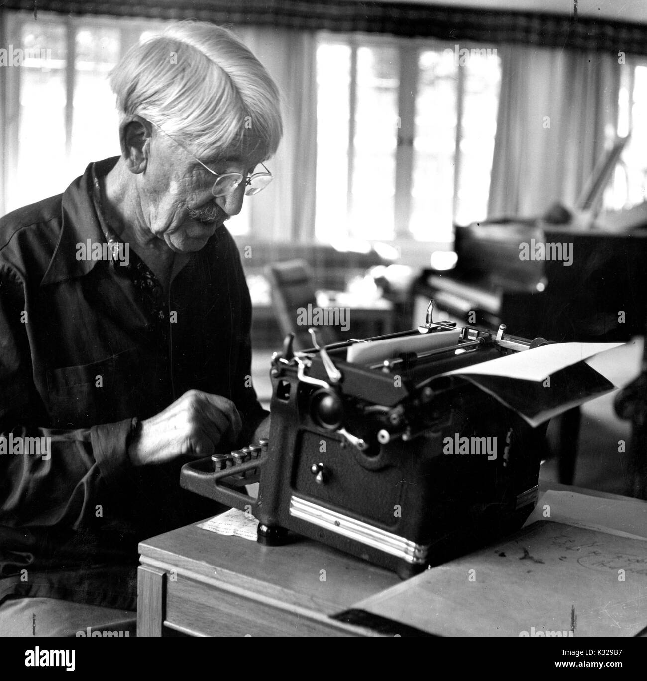 Candid portrait of American philosopher, psychologist, and educational reformer John Dewey sitting at a typewriter, 1946. Stock Photo