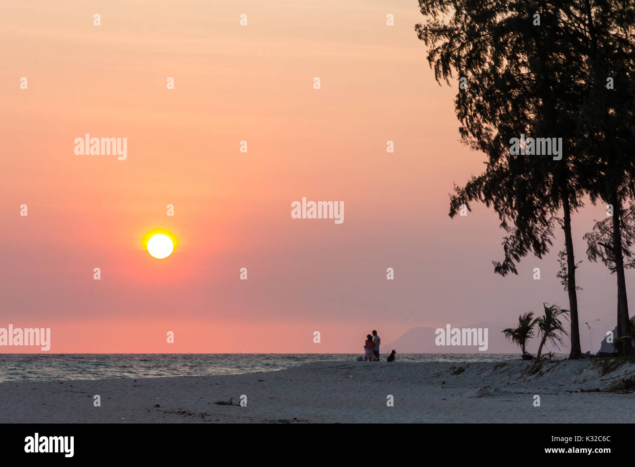 Couple and dog watching the sunrise, Sunrise beach, Koh Lipe, Satun, Thailand Stock Photo