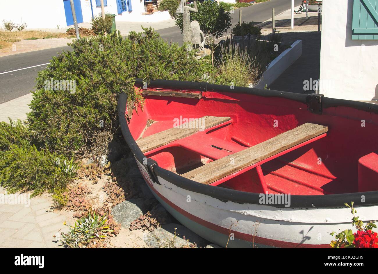 old wooden boat lying on the shore in the bushes of flowers and sand ...