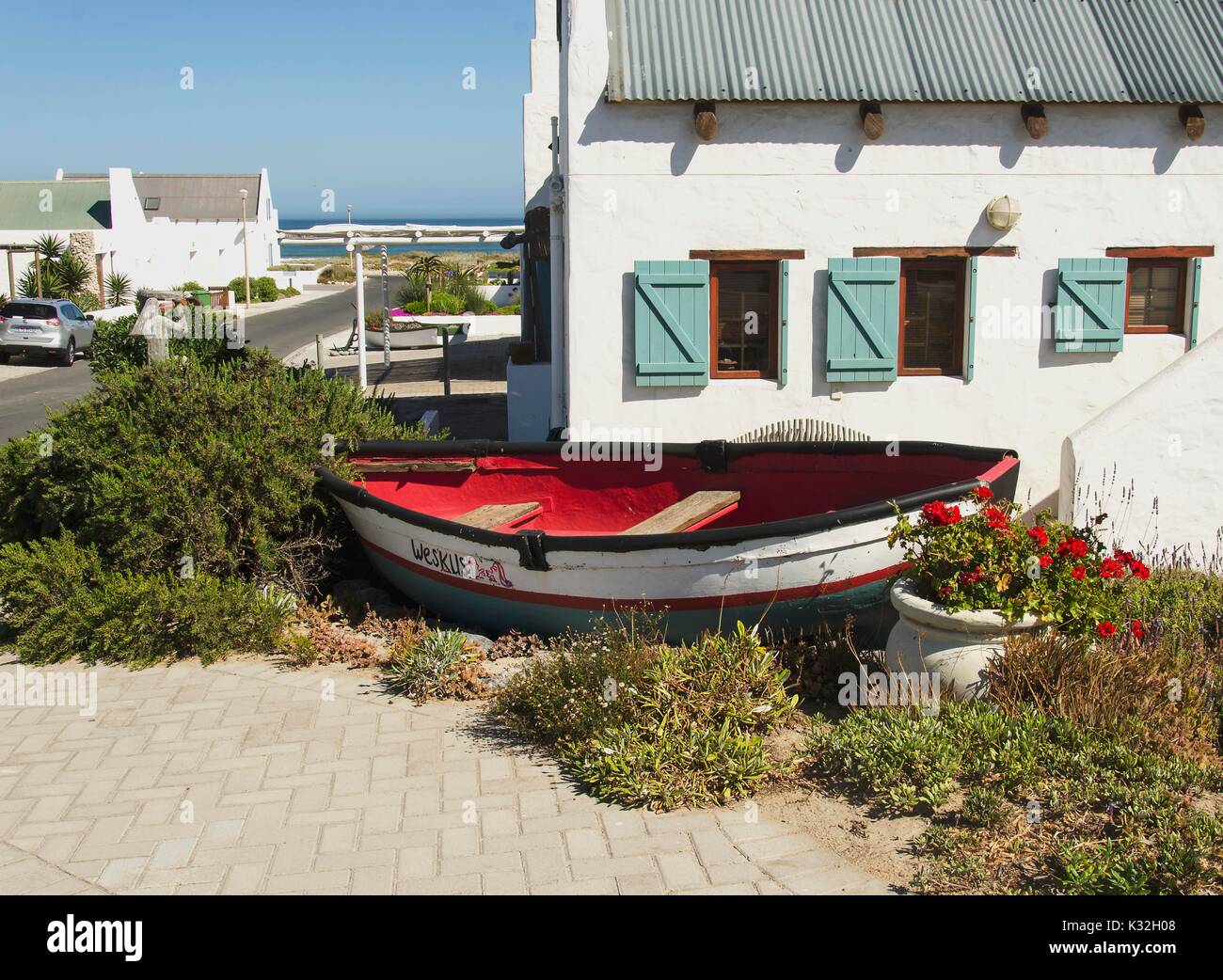 old wooden boat lying on the shore in the bushes of flowers and sand ...