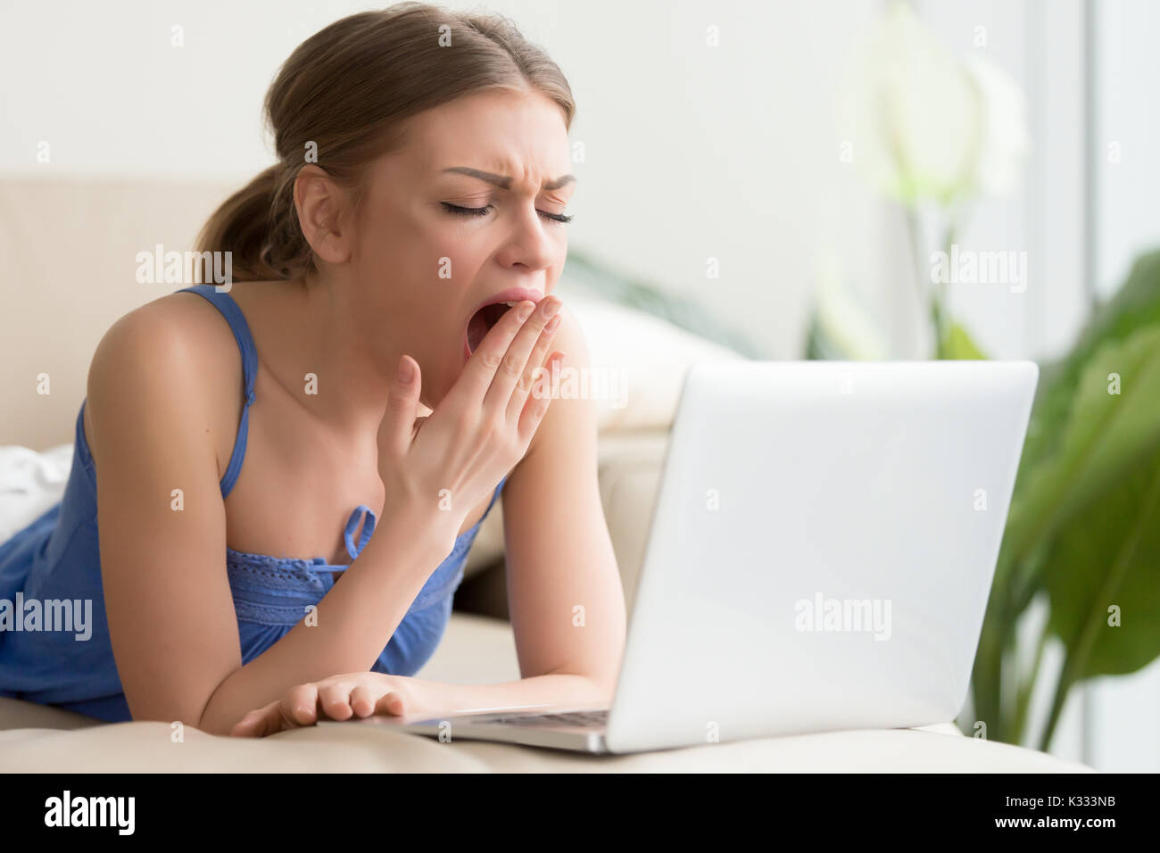 Tired woman yawning after too long work on laptop Stock Photo