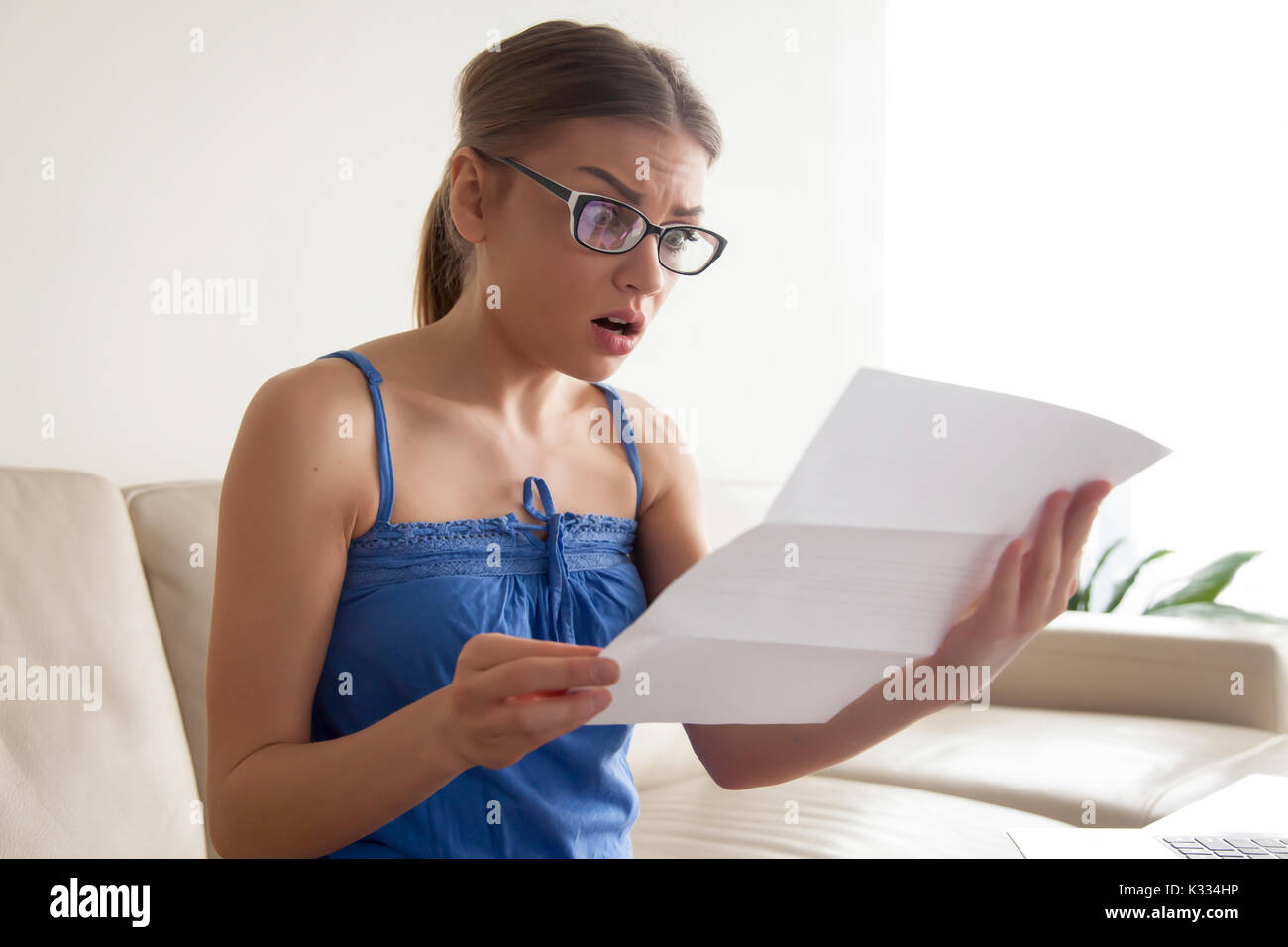 Woman shocked because of written notice from bank Stock Photo