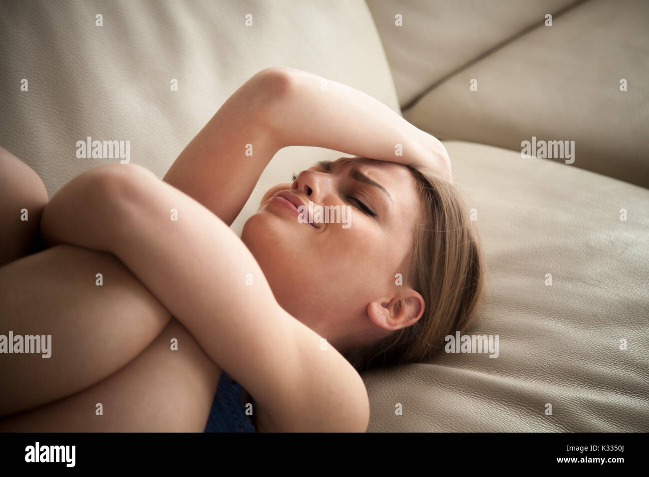 Stressed lady lying on couch at home and crying Stock Photo