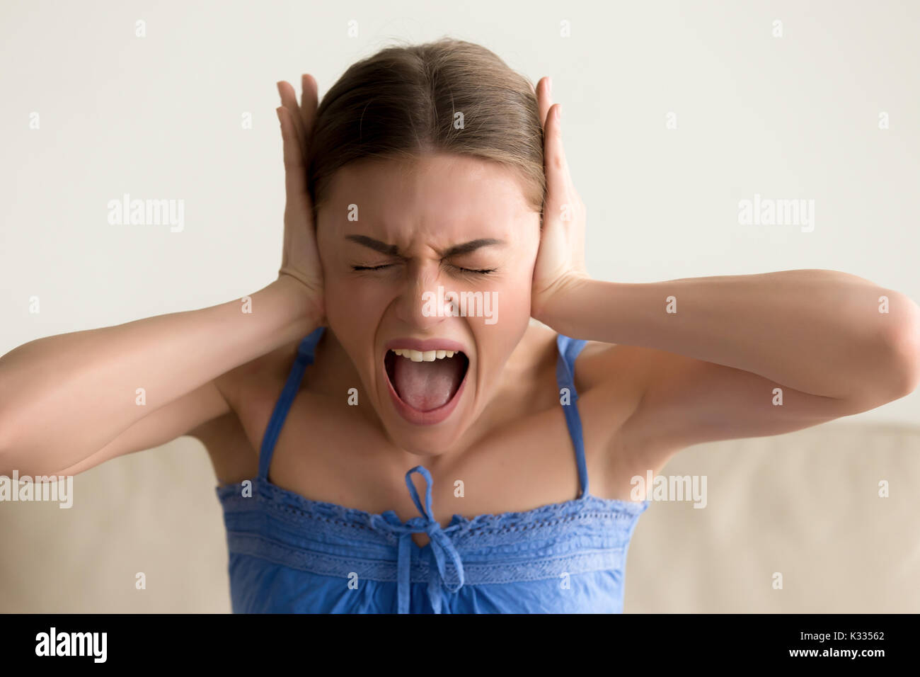 Depressed woman closing ears and screaming Stock Photo