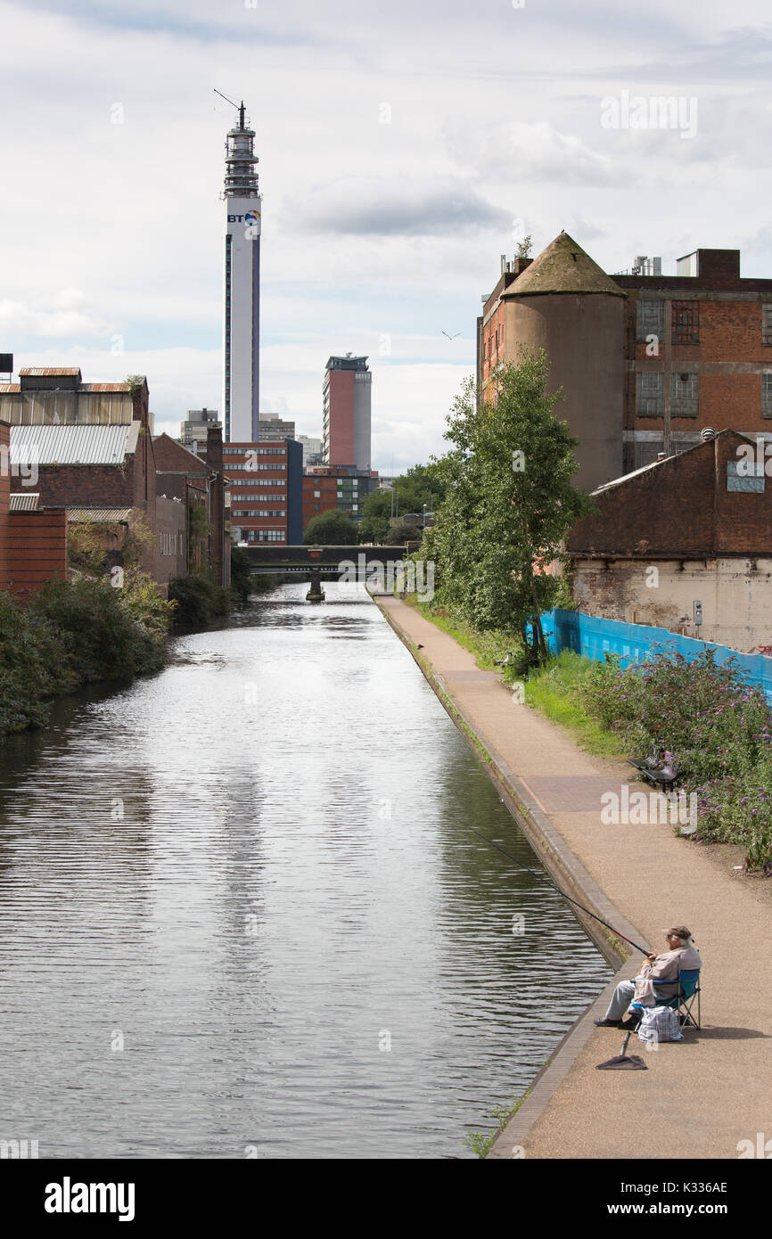 A fisherman fishing on the Birmingham and Fazeley canal in the centre of Birmingham Stock Photo