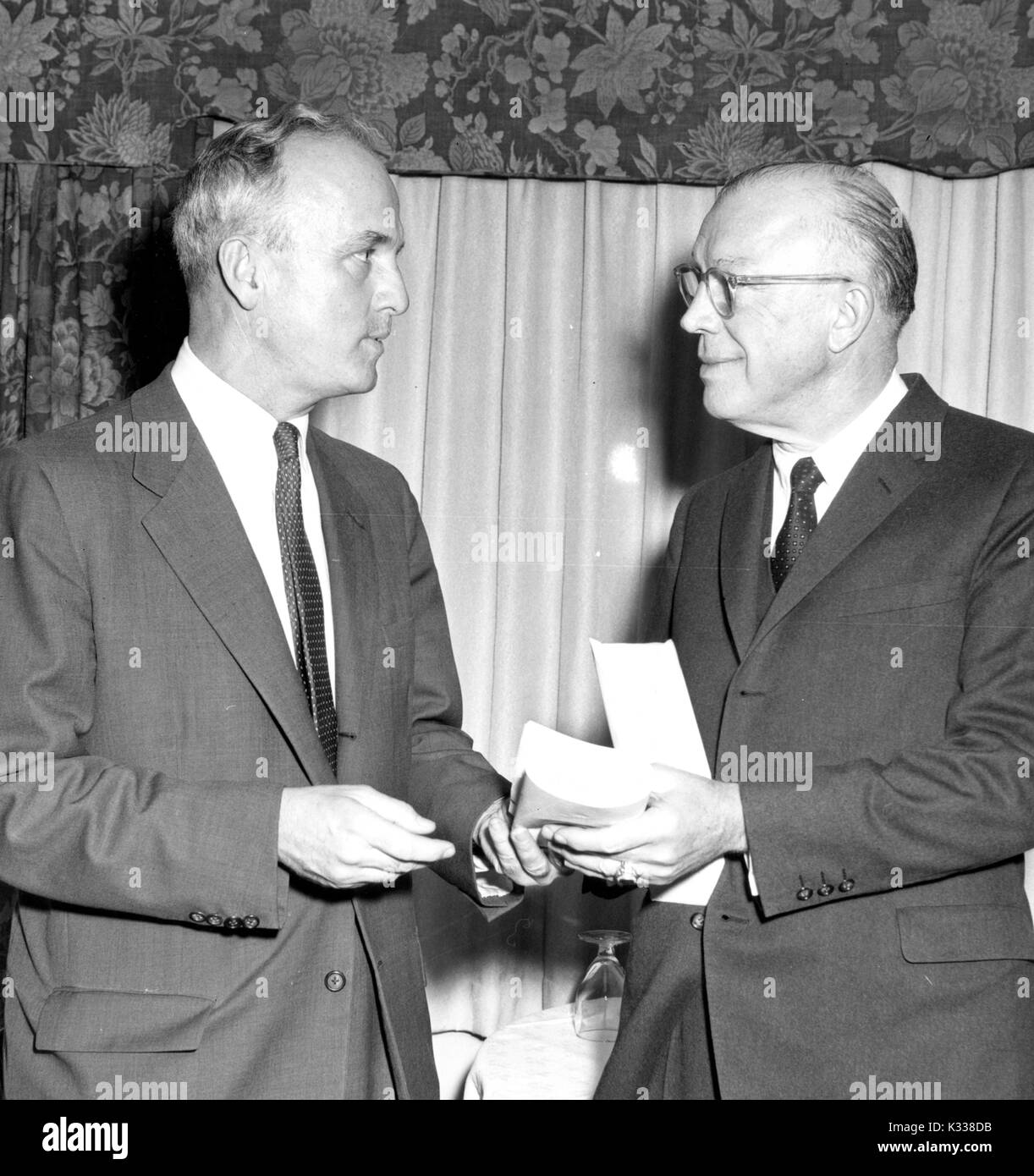 Milton Stover Eisenhower, President of Johns Hopkins University, stands wearing a suit while accepting an endowment from Congressman Peter H B Frelinghuysen from New Jersey, with a floral valence and curtain behind them, Baltimore, Maryland, 1965. Stock Photo