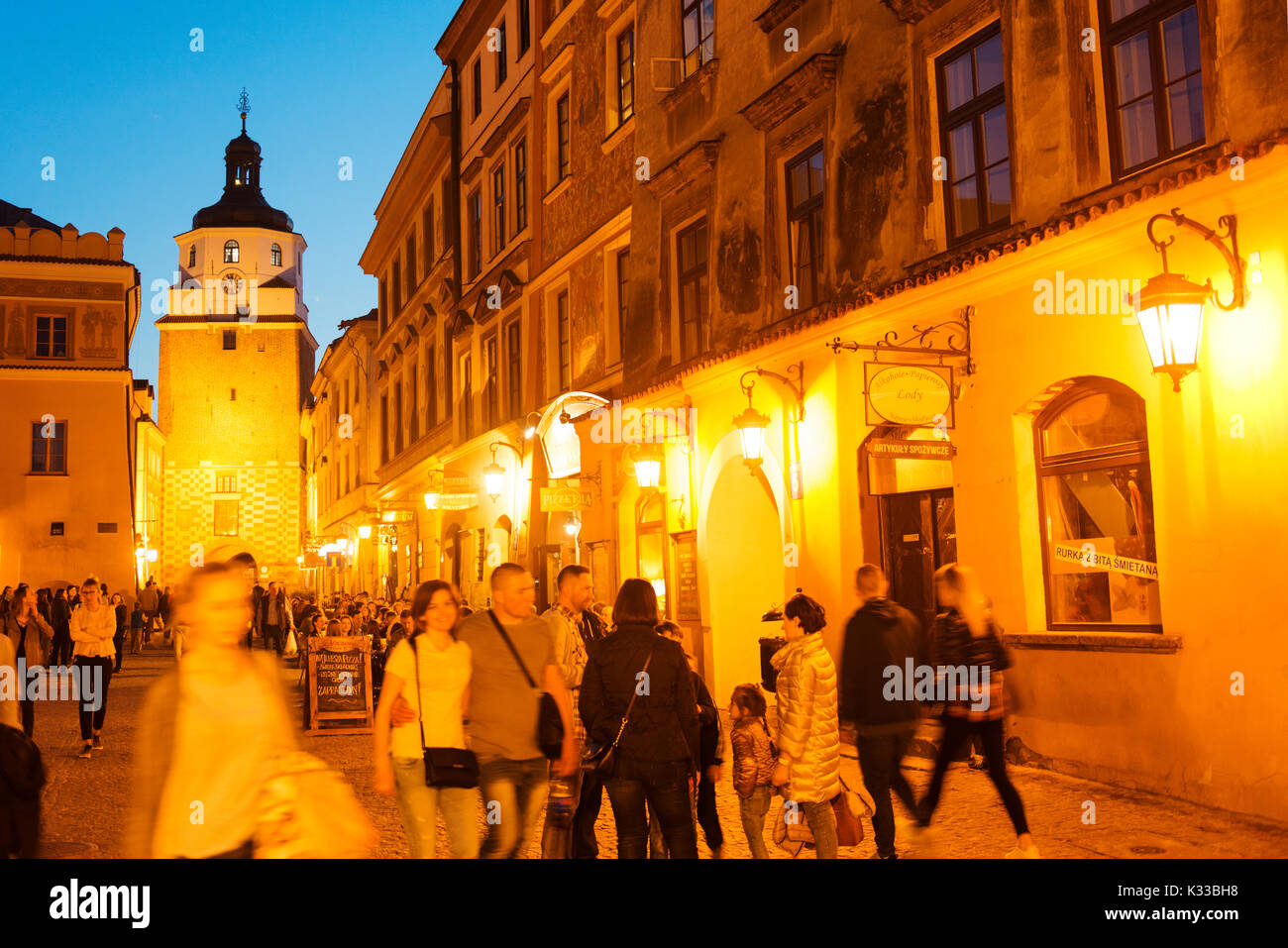 Locals, visitors and holiday makers walk in the evening in Lublin's old town.  The Krakow Gate is in the background. Stock Photo