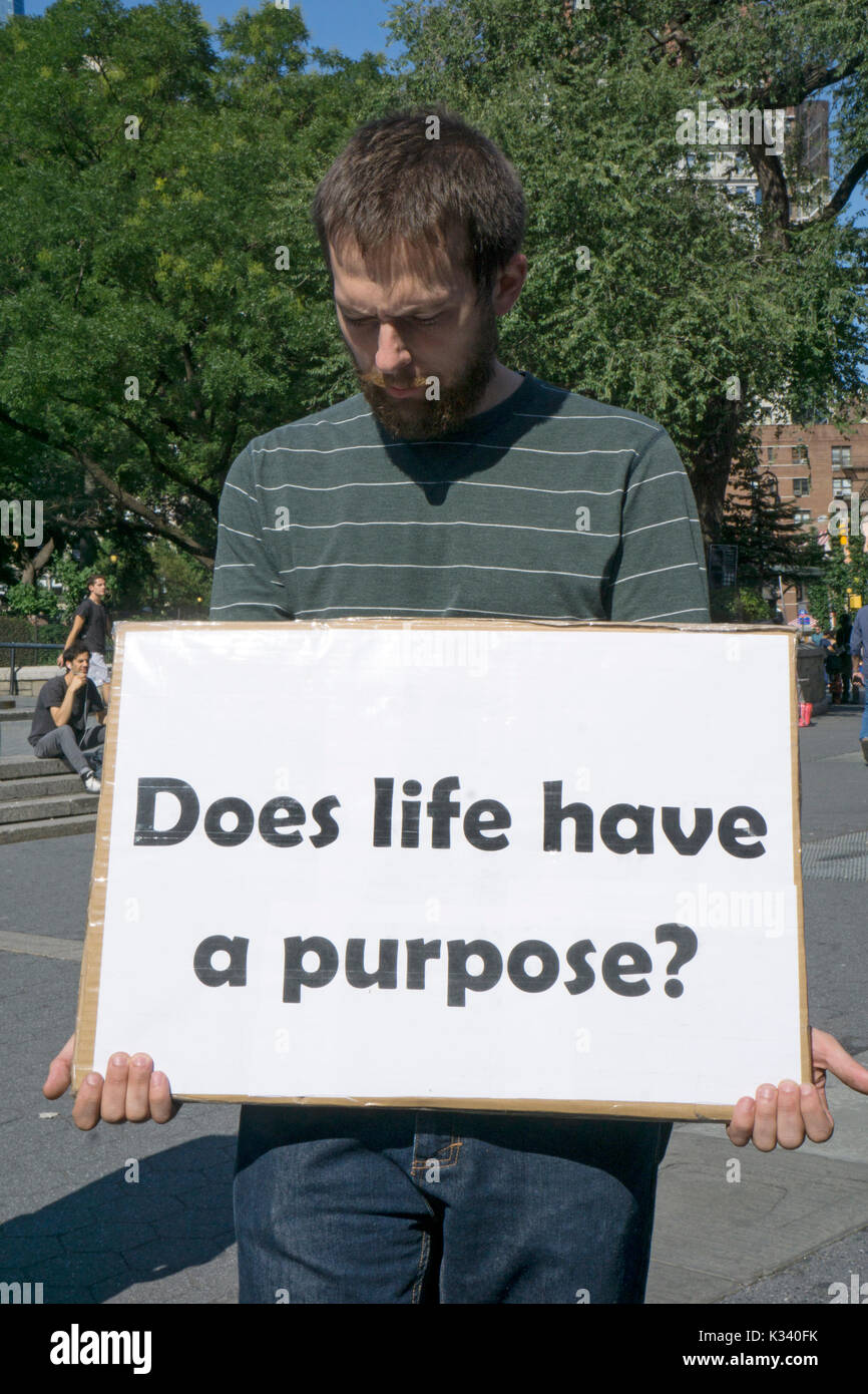 A man in Union Square Park holding a mysterious sign about life's purpose.. New York City. Stock Photo
