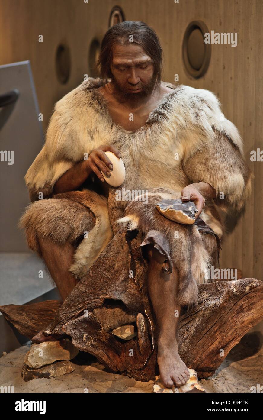 Neanderthal Man working with stones, chipping off arrow heads and knifes Stock Photo