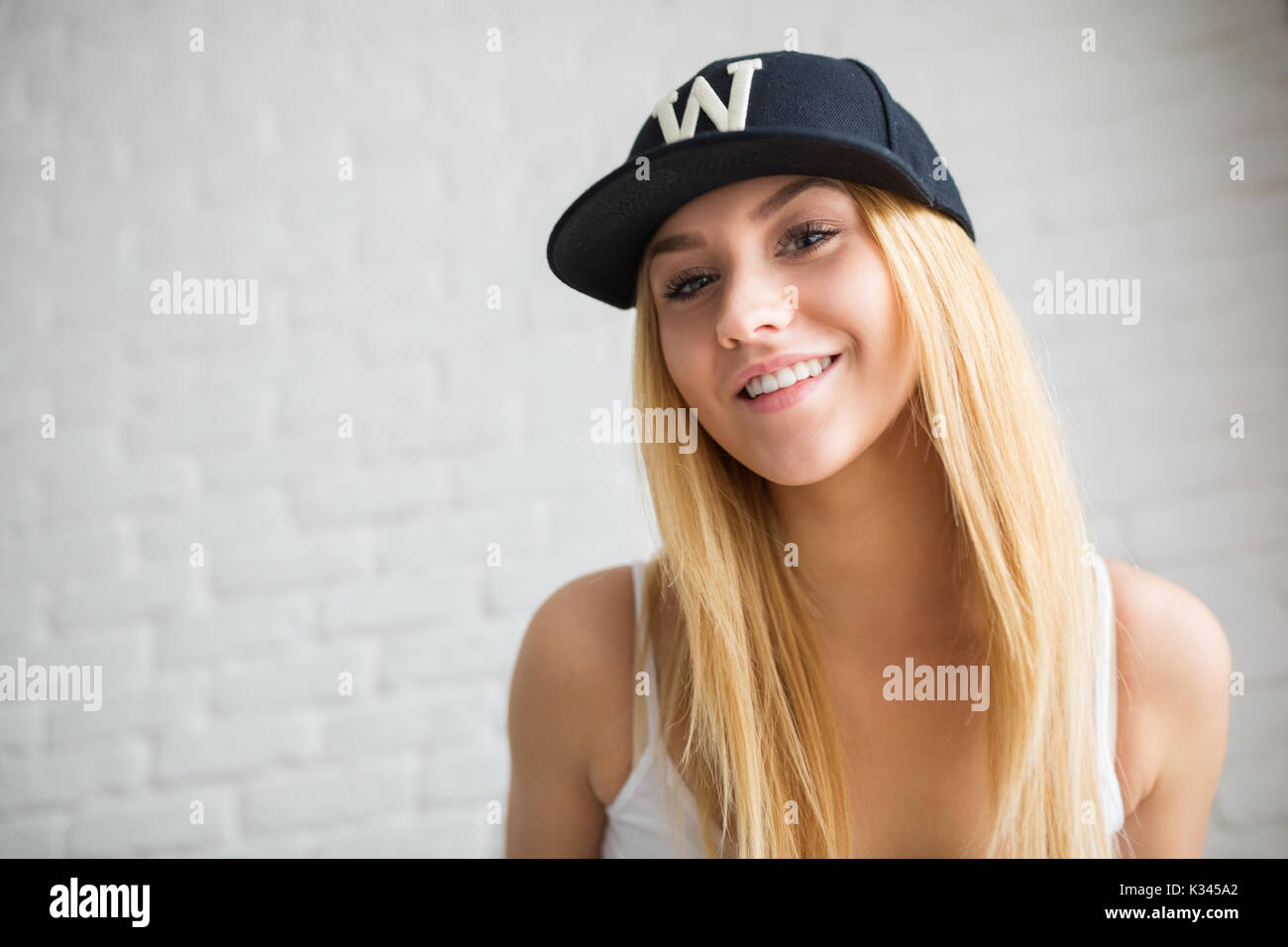 A photo of young, beautiful woman wearing black cap. She's posing to