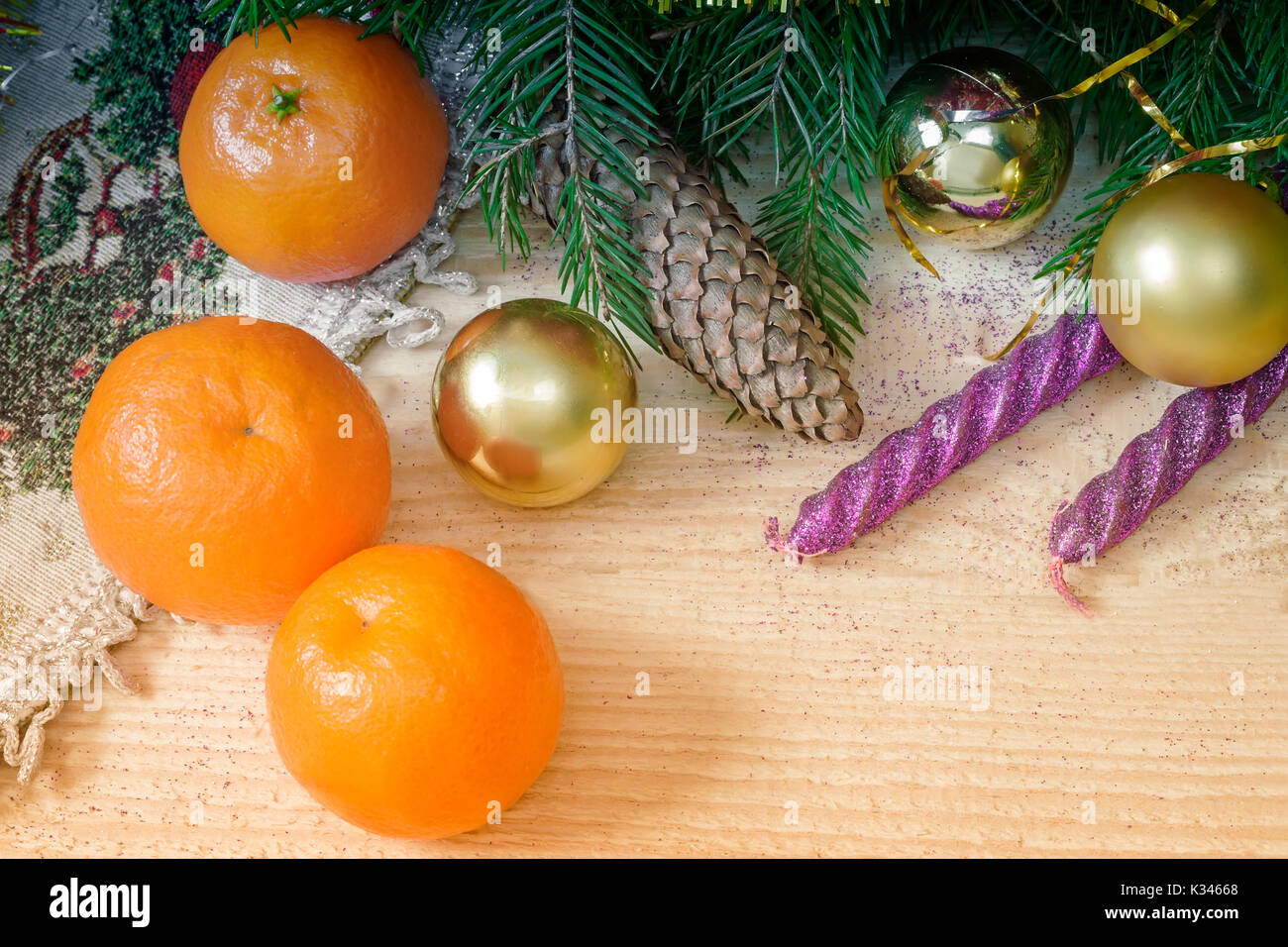On a wooden table beautifully set decorations and gifts for Christmas, the New year pine branches, cones, shiny balls, candles, confetti. Stock Photo