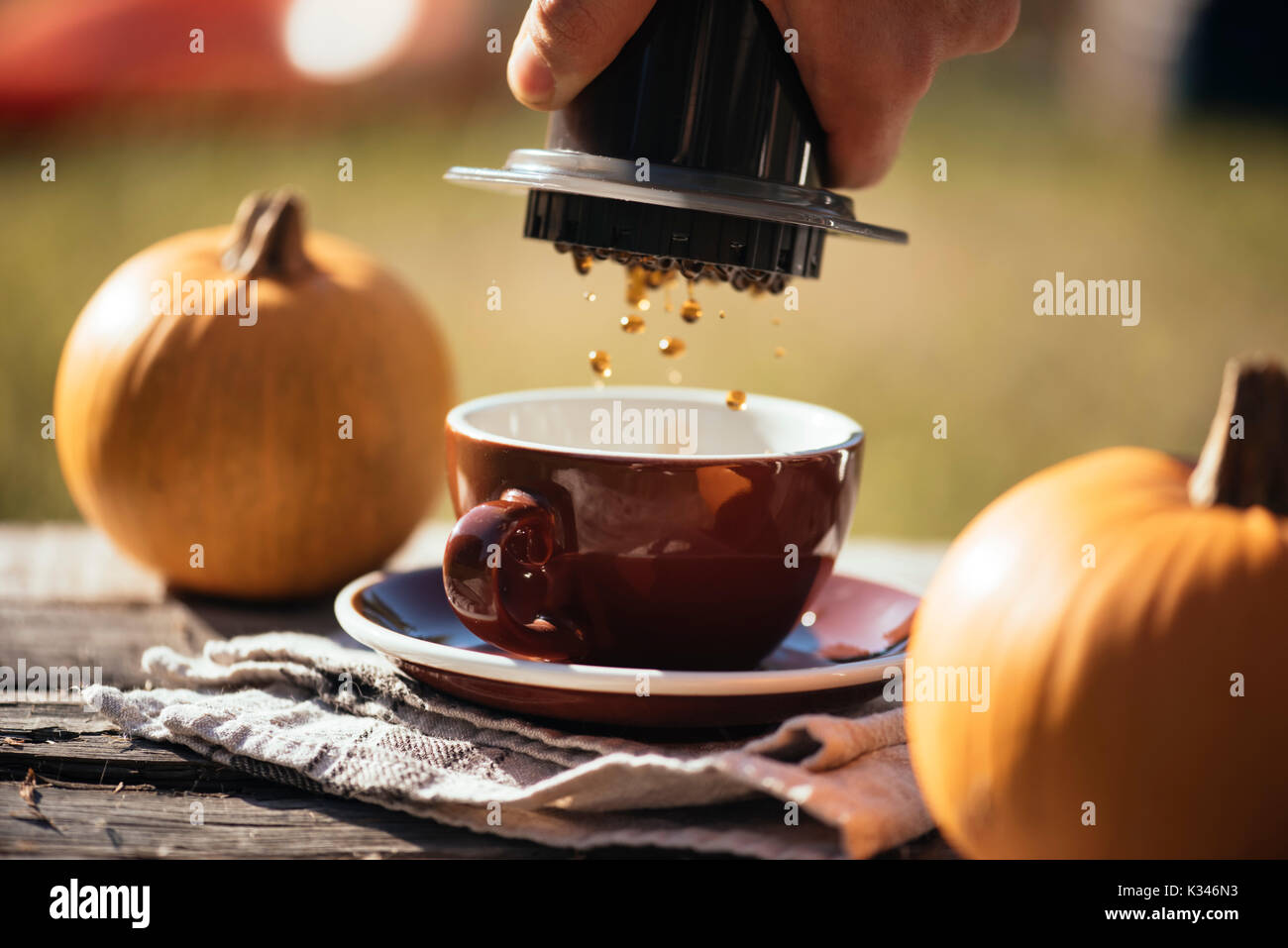 Man brewing filter coffee outdoor, at the autumn coffee picnic, on the old damaged wooden table background. Coffee drips captured in motion in the pro Stock Photo