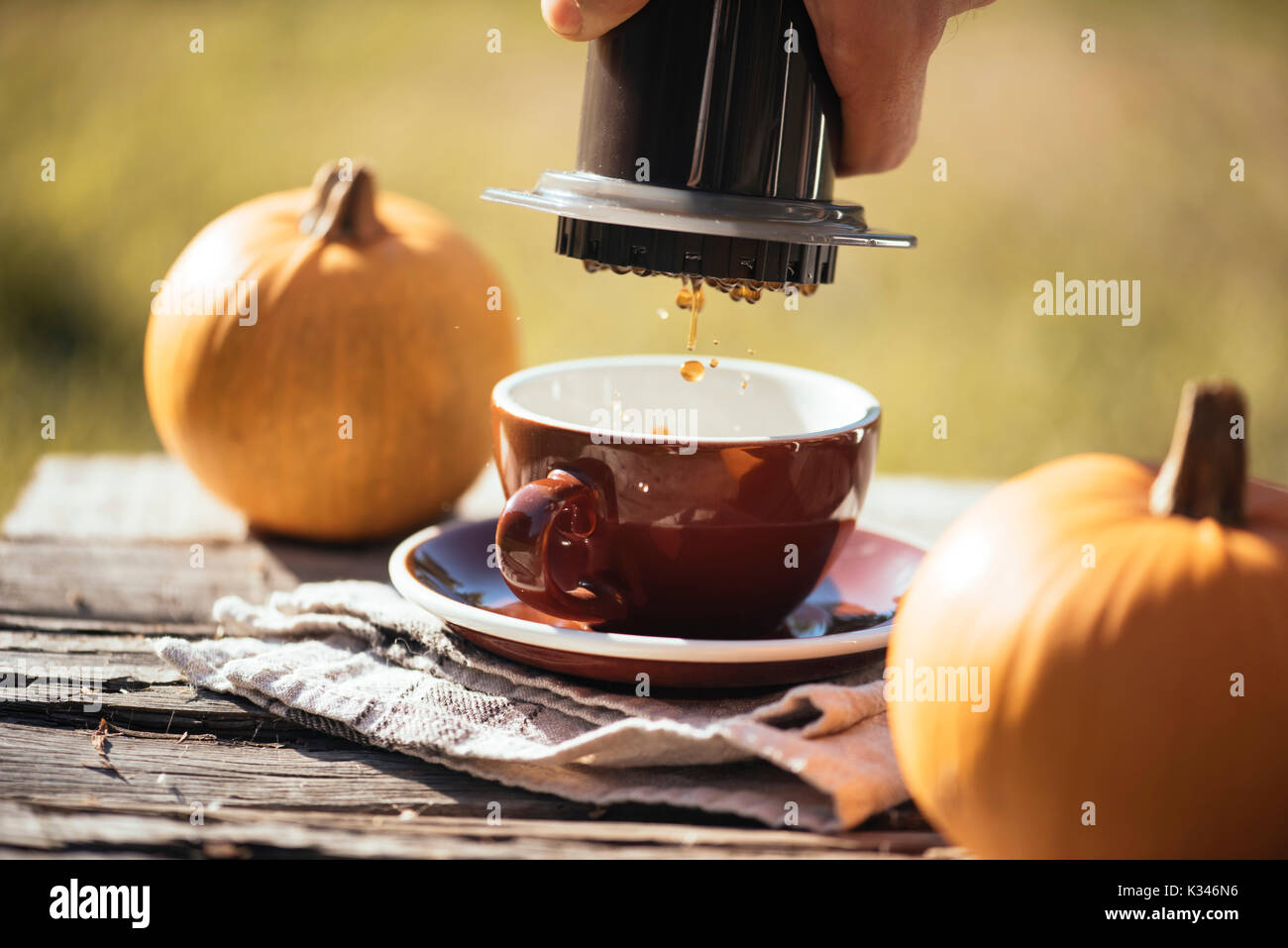 Man brewing filter coffee outdoor, at the autumn coffee picnic, on the old damaged wooden table background. Coffee drips captured in motion in the pro Stock Photo