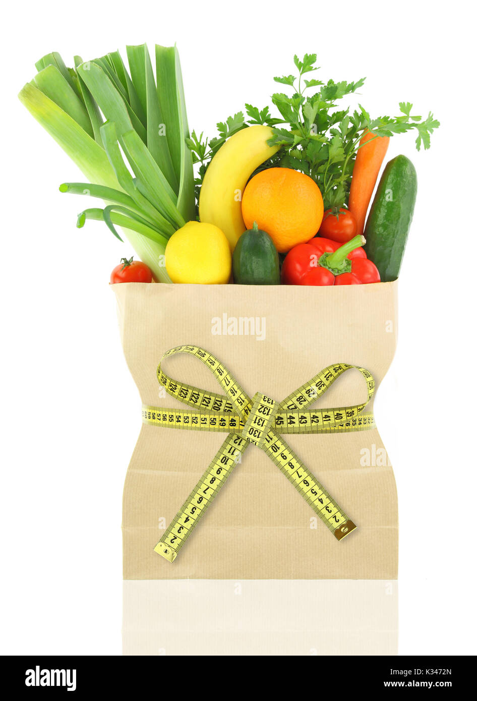 Fresh vegetables and fruits in a paper grocery bag with measuring tape ...