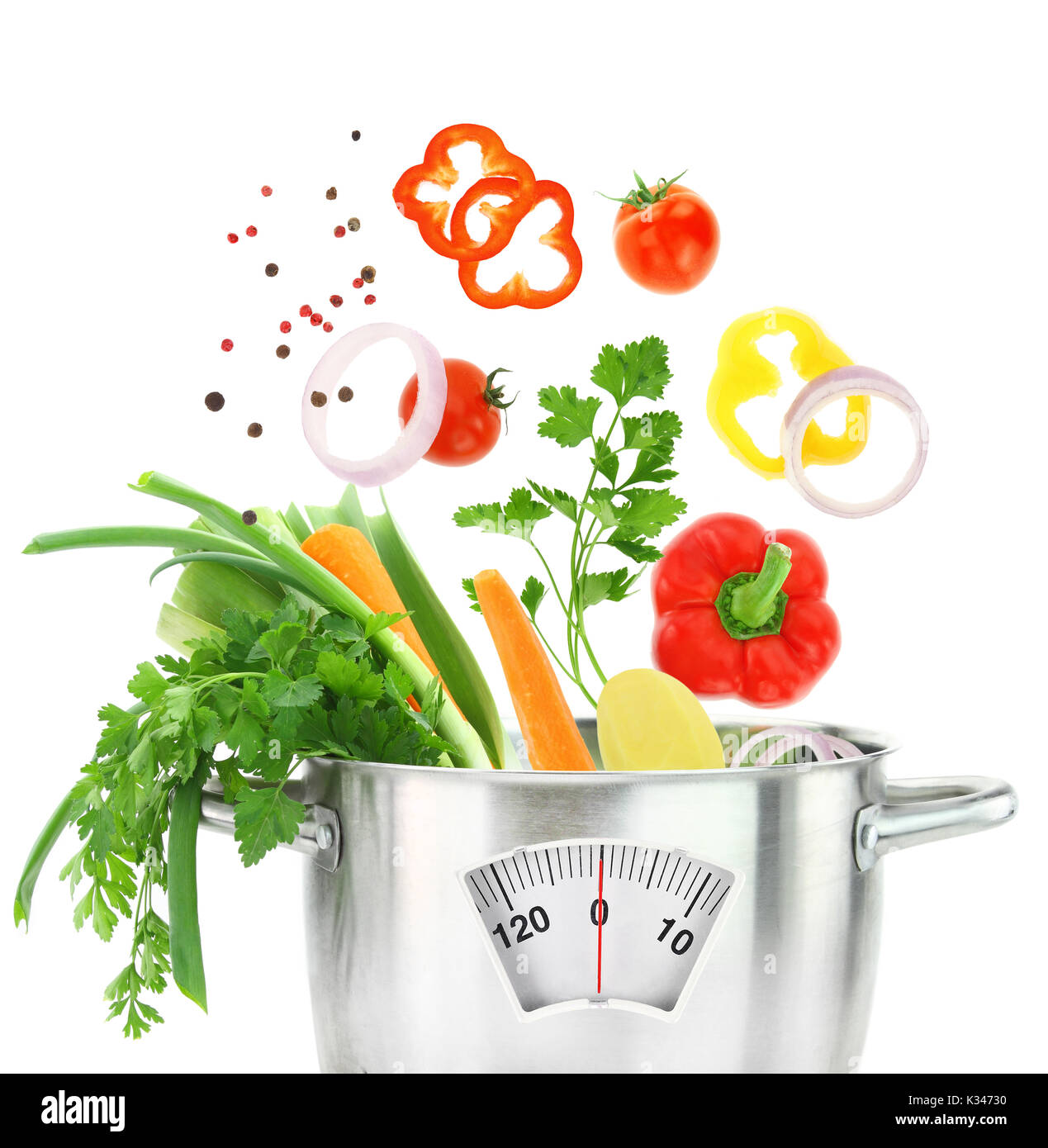 Fresh vegetables falling into a casserole pot with weight scale Stock Photo
