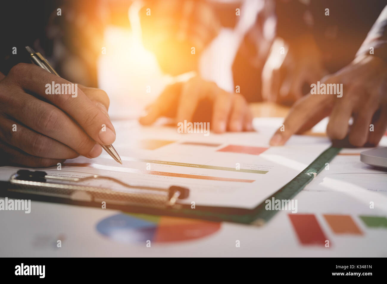 Group of people analyzing data and pointing pen at charts and graph to find out the result. business discussion concept Stock Photo