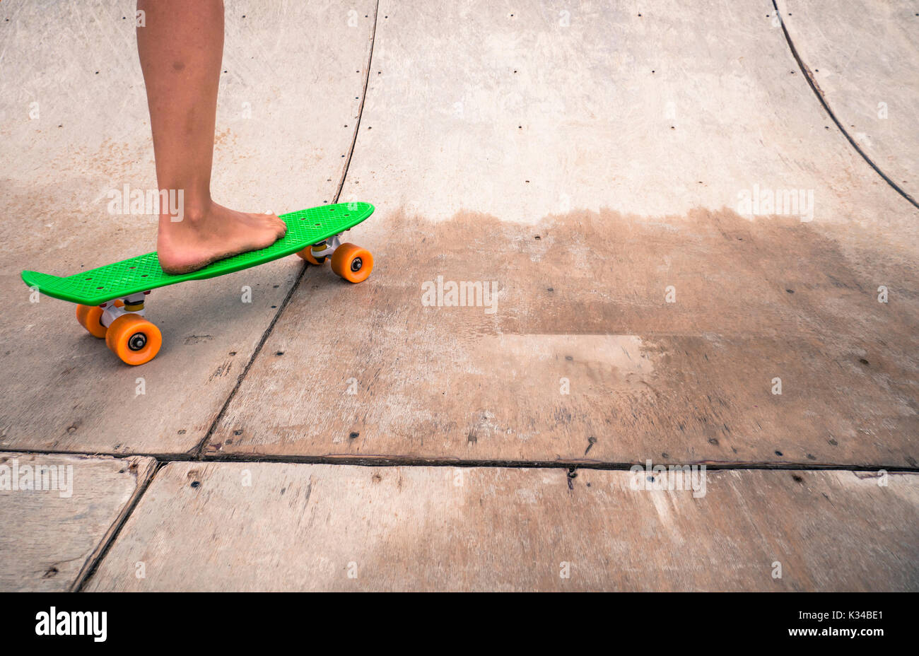 Woman riding a penny board on a wooden half-pipe. Stock Photo