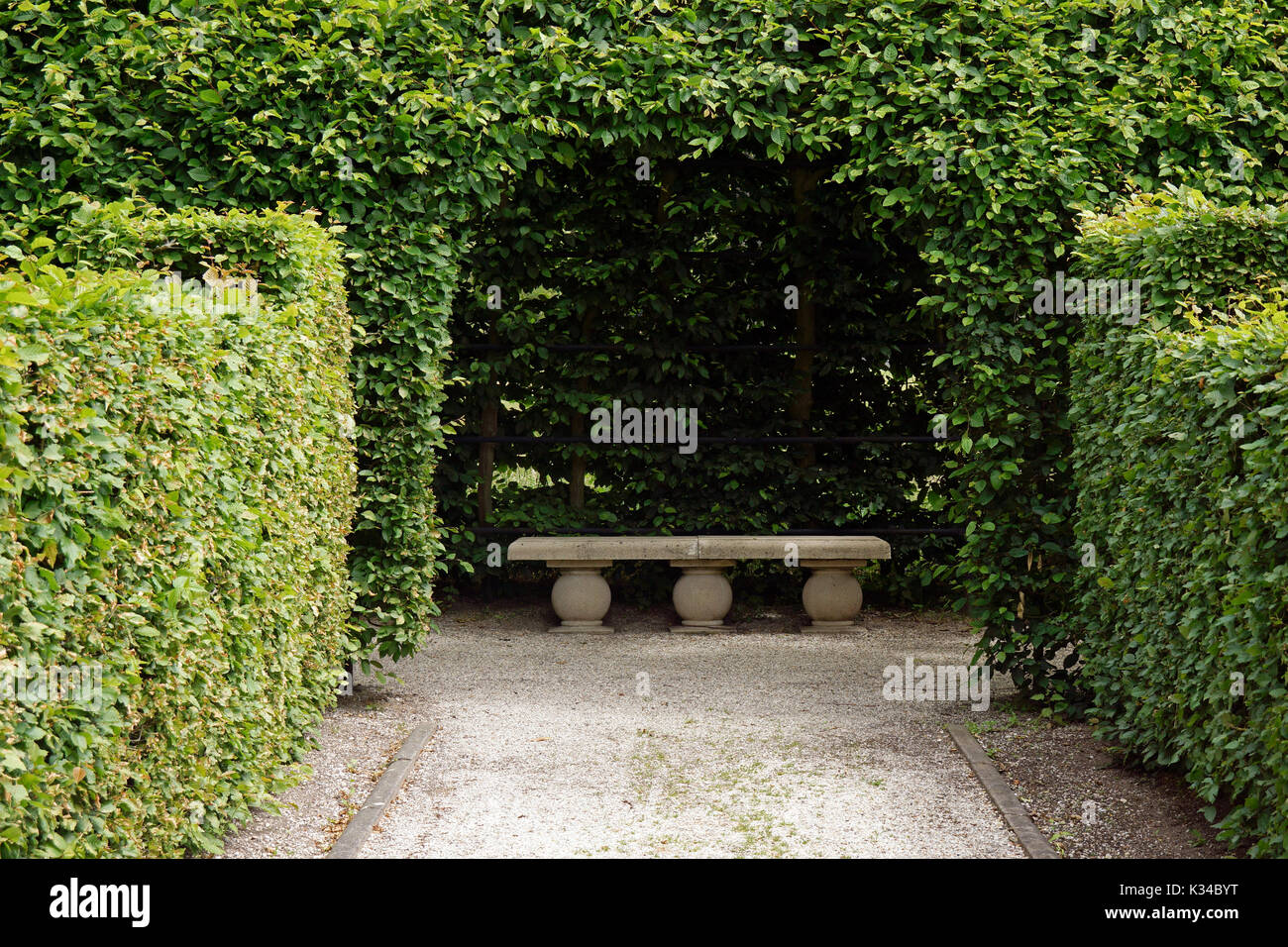 Stone Bench Under An Arch In A Formal Garden Stock Photo