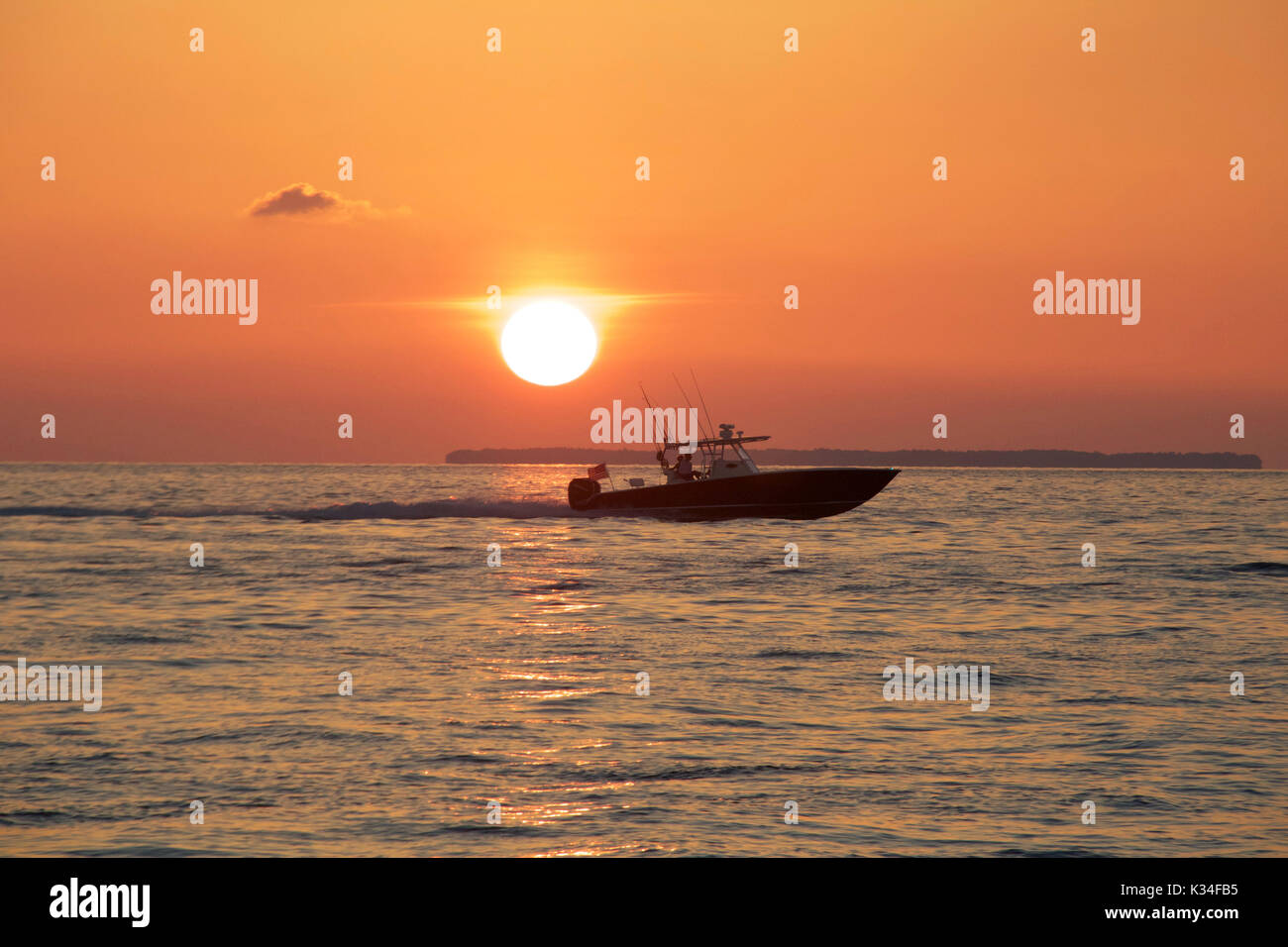 A powerboat speeds by at sunset in the Florida Keys Stock Photo